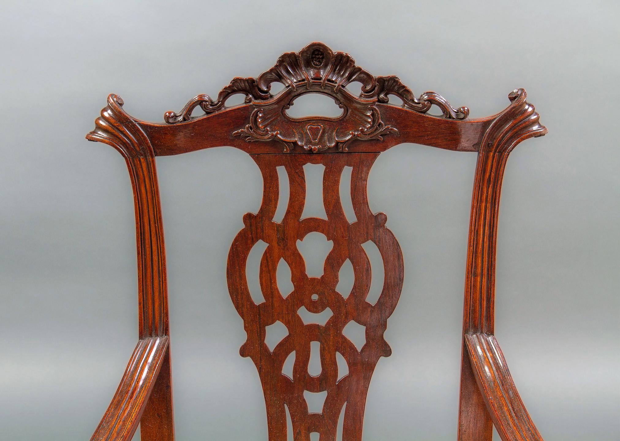 Each chair with foliate ribbon crest rail, Fret work splat, down swept channelled arms and scrolled handholds, the shaped balloon seat framed by an acanthus and shell carved seat rail, all supported on cabriole legs decorated with anthemion and