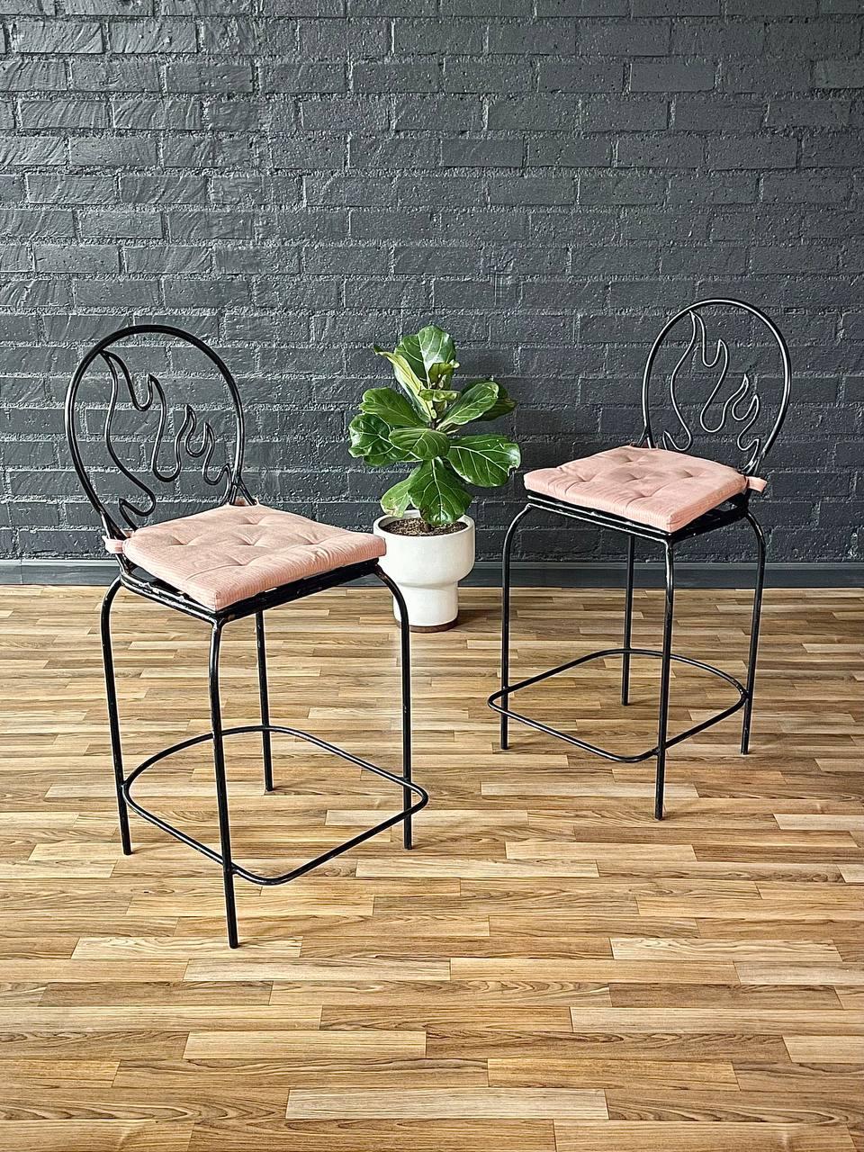 Cette paire de tabourets de bar post-moderne de style Memphis, datant des années 1980, présente une structure audacieuse et sculpturale en fer forgé avec un dossier en forme de flamme qui attire l'attention. Le design ludique reflète l'influence du