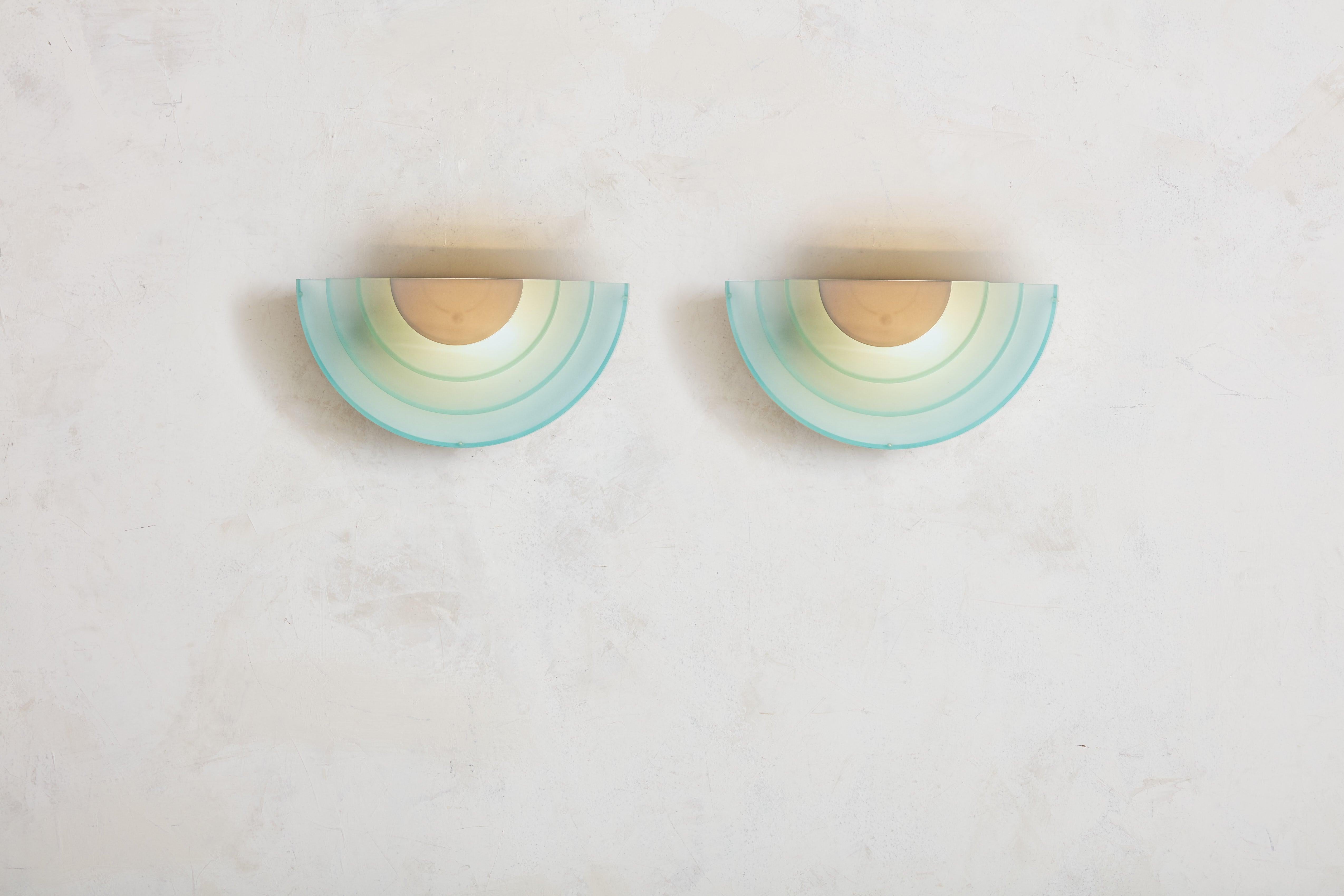 An exquisite pair of Postmodern sconces produced by IKEA in the 1980s. Before IKEA became global, the mid-century company only had stores located in Sweden. Each sconce features an aqua and white hued glass shade, composed of layered concentric
