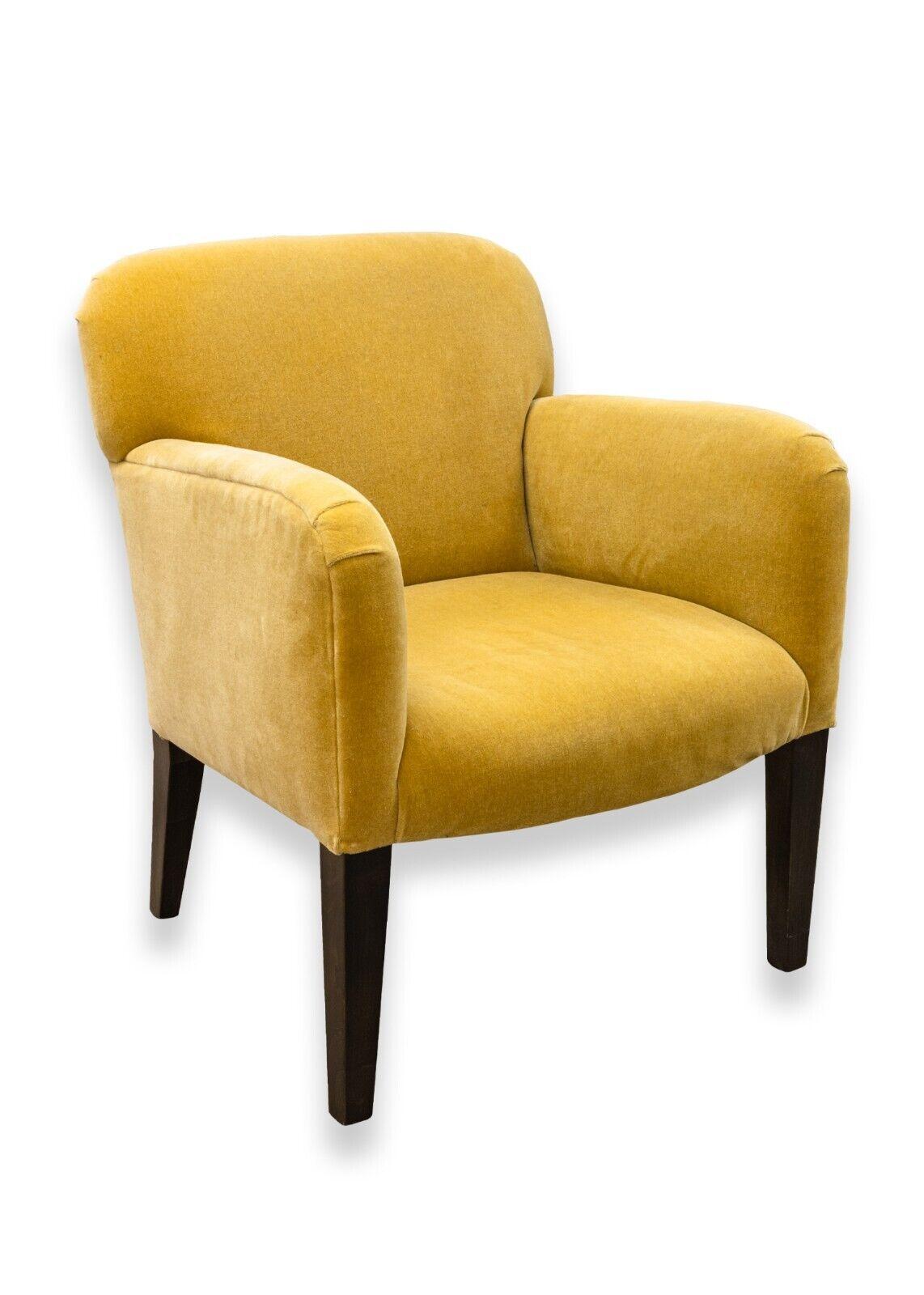 A pair of post modern yellow gold armchairs. A delightful set of armchairs with a very bright yellow/gold upholstery, black wooden legs, and super comfy cushions. These chairs are in great condition. There are some very slight scuffs and scratches