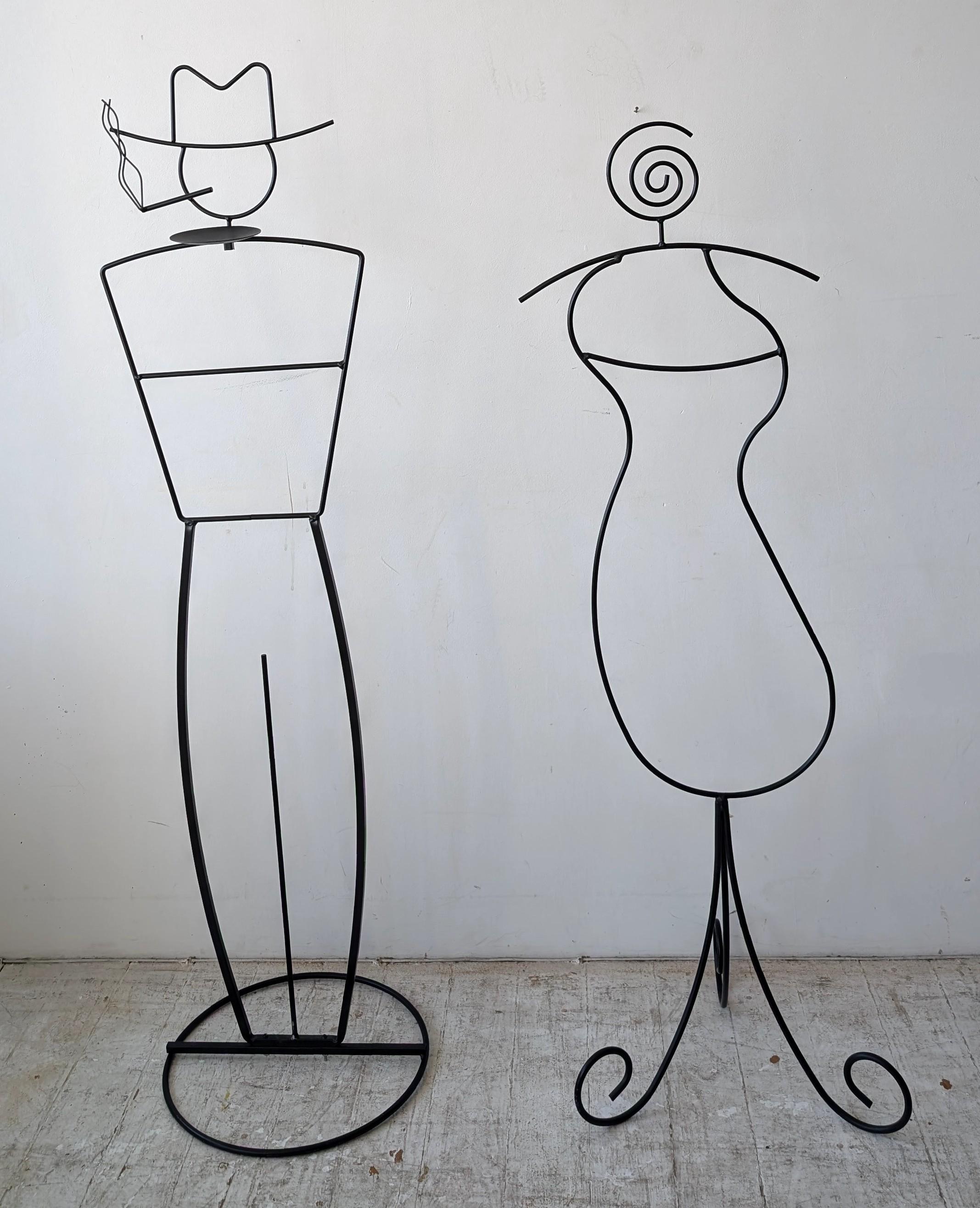 Quirky pair of postmodern John Risley style black metal figural valet stands, USA 1980s
The smoking man figure has an ashtray / key dish.

Dimensions: man is 153cm high, 41cm wide; woman is 141cm high, 46cm wide