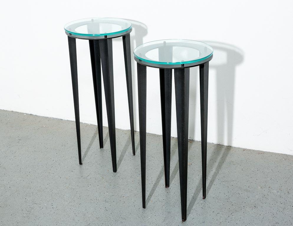 Ein Paar hohe postmoderne Tische. Spitz zulaufende Beine aus schwarzer Emaille mit runder Glasplatte.