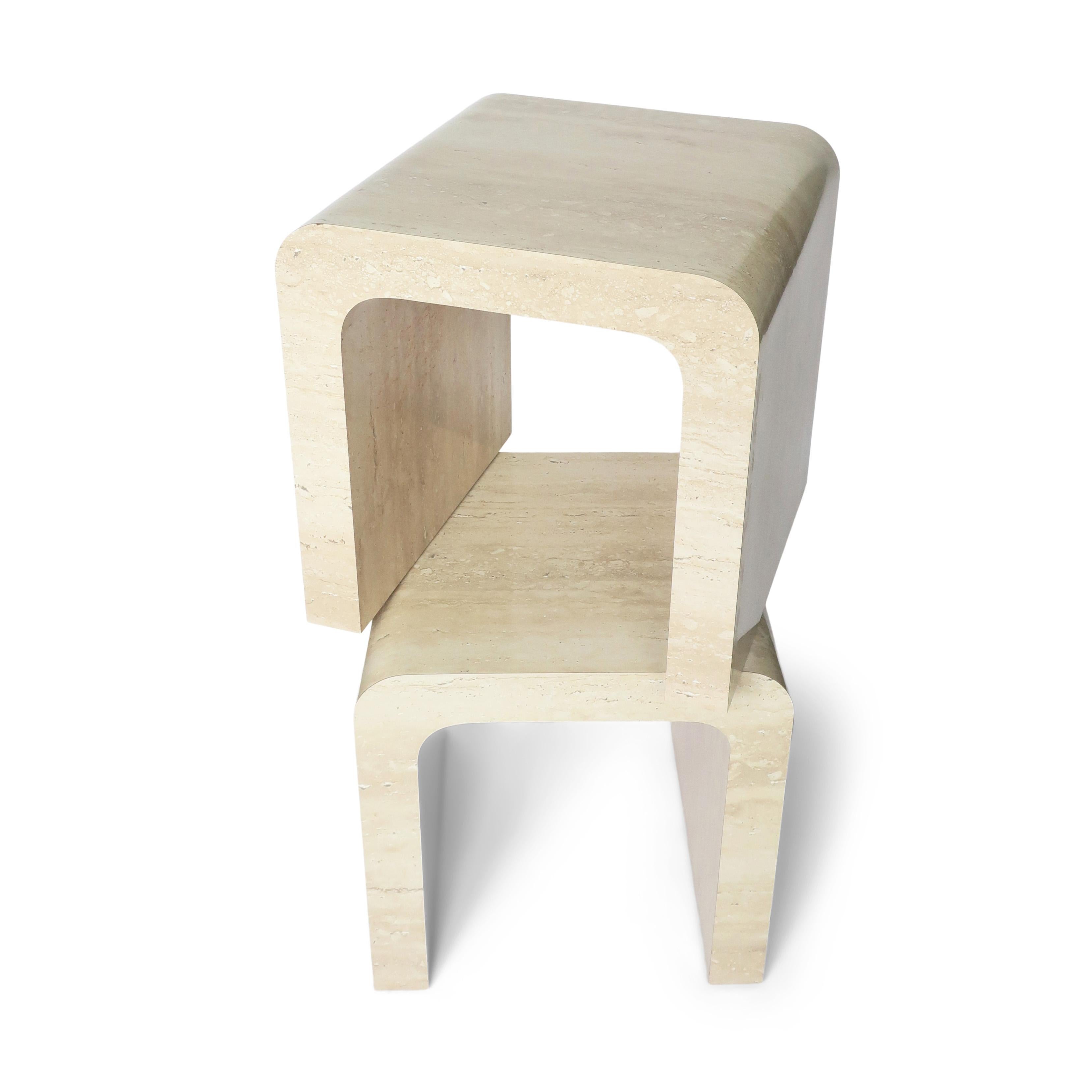 A sleek pair of postmodern waterfall tables, most likely from the 1980s, in the sculptural style of Karl Springer.  The tables are covered in a travertine patterned laminate over wood.  They're versatile enough to be side tables or end tables, even