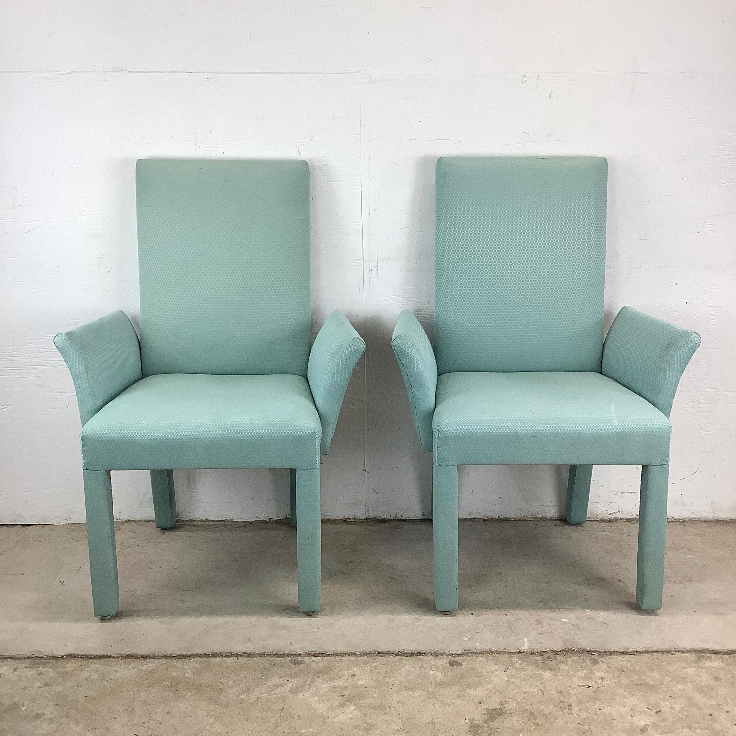 A sculptural nod to postmodern design, this pair of fully upholstered armchairs features strong architectural lines softened by an inviting aqua textile. With a commanding silhouette and avant-garde attitude, the chairs suggest influences from
