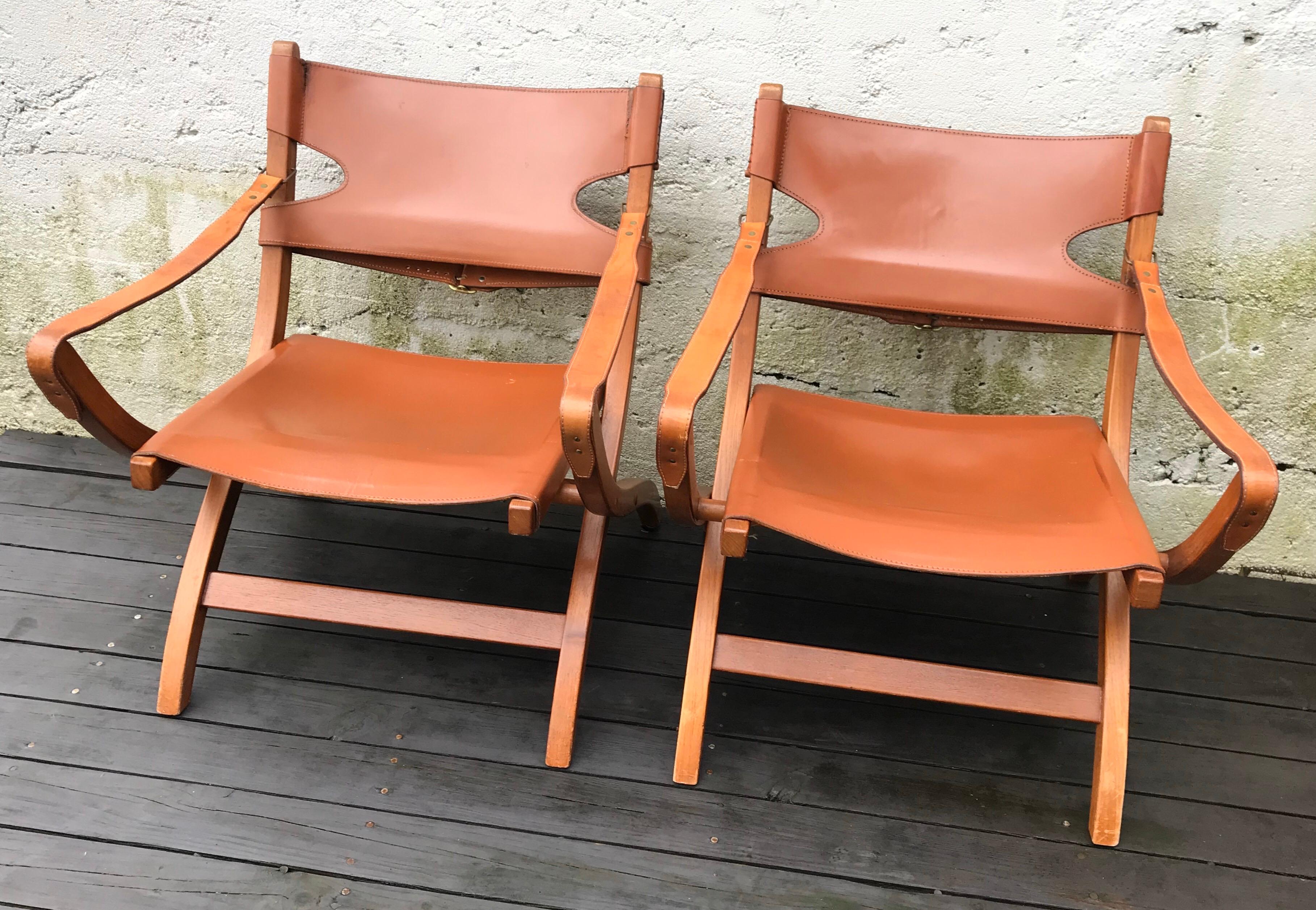 Beautiful pair of Poul Hundevad campaign X-leather folding lounge chairs with X-shaped legs, inspired by ancient Egyptian thrones and chairs. The frames are solid oak, seats and back rests are made of cognac colored saddle leather. Natural leather