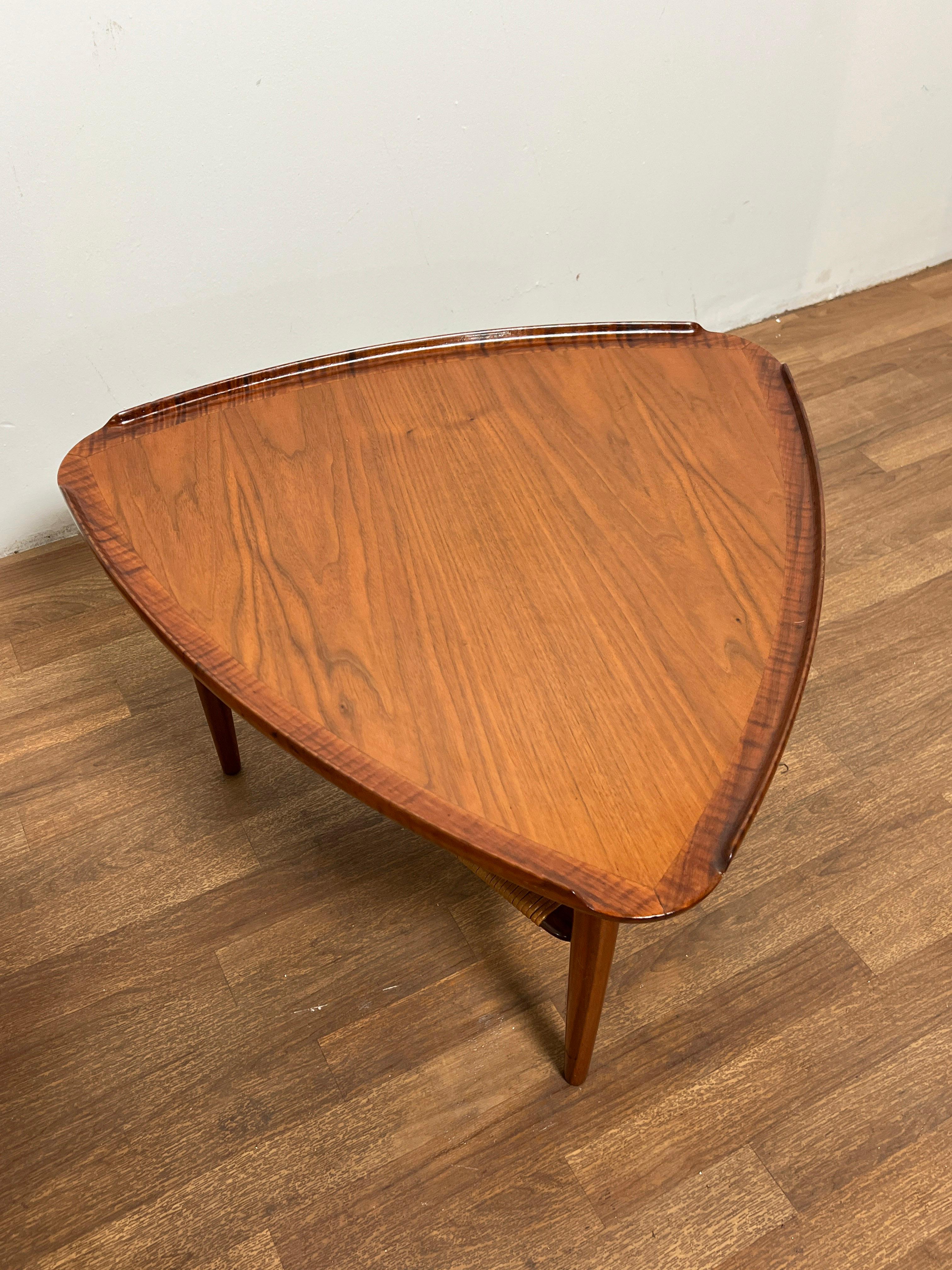 Pair of tripod side tables in teak with cane undershelves, a classic design by Poul Jensen for Selig, Denmark, circa 1960s.  Commonly referred to as the 