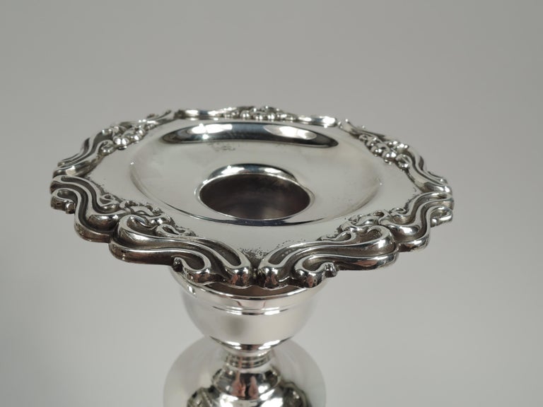 Pair of pretty Edwardian sterling silver candlesticks. Urn socket with detachable bobeche mounted to tapering shaft on domed foot. Bobeche and foot have applied rim scrolls. Fully marked including maker’s stamp for Mueck-Cary, a New York company