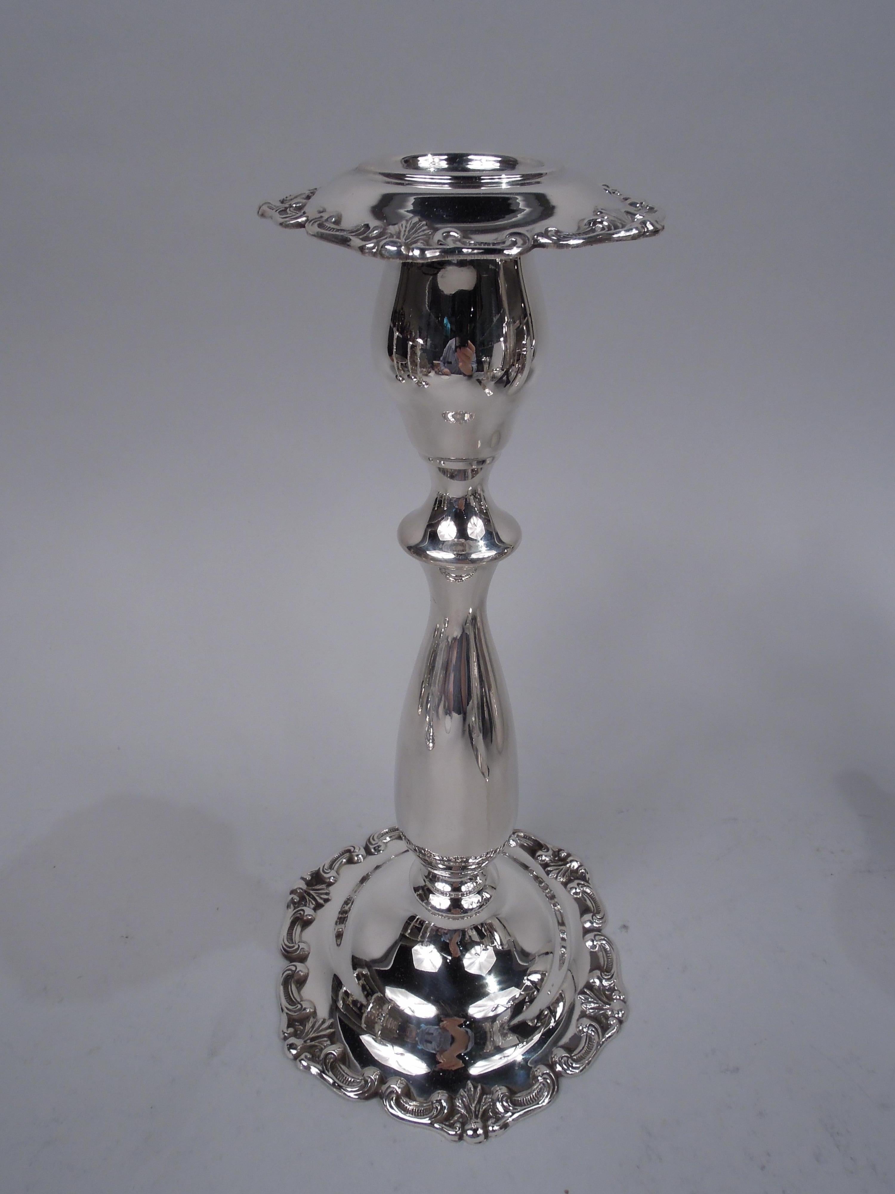 Pair of pretty Edwardian sterling silver candlesticks. Made by Fisher Silversmiths, Inc. in Jersey City, ca 1950. Each: Ovoid socket with detachable and turned-down bobeche; baluster shaft on domed foot. Rims have applied shells and scrolls. Fully