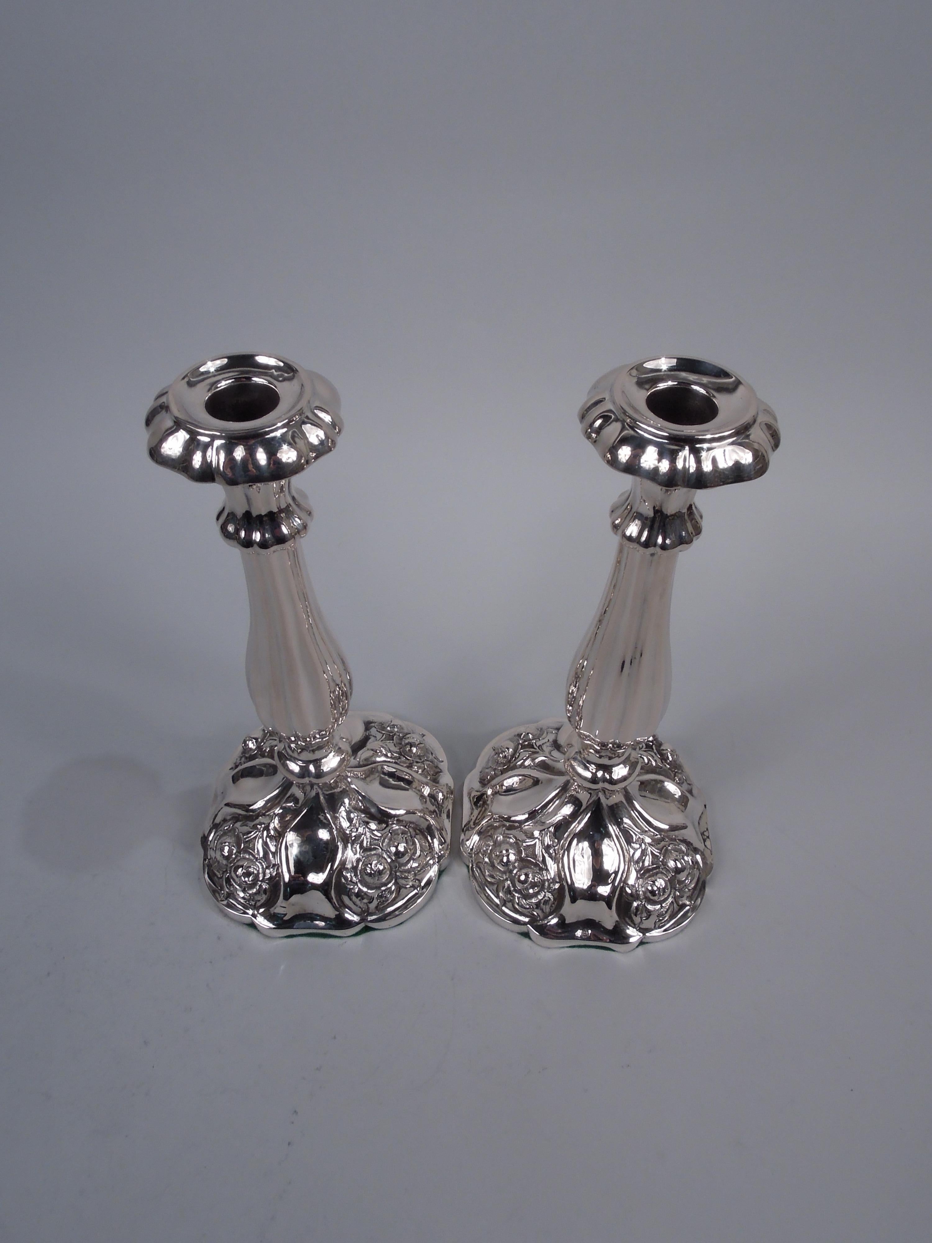 Pair of pretty Austrian Biedermeier Classical silver candlesticks, 1863. Each: Tapering socket with turned-down rim and overhanging base mounted to knopped baluster shaft on domed and curvilinear foot with stippled flowers at corners. Fluting and