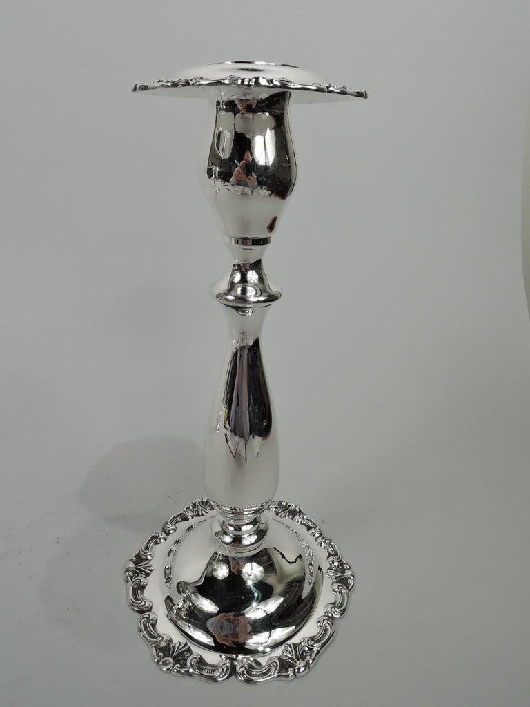 Pair of Georgian-style sterling silver candlesticks. Made by Fisher Silversmiths, Inc. Each: Baluster shaft on domed foot with applied scroll and leaf rim. Socket detachable and turned-down with same. Pretty and old fashioned. Fully marked including