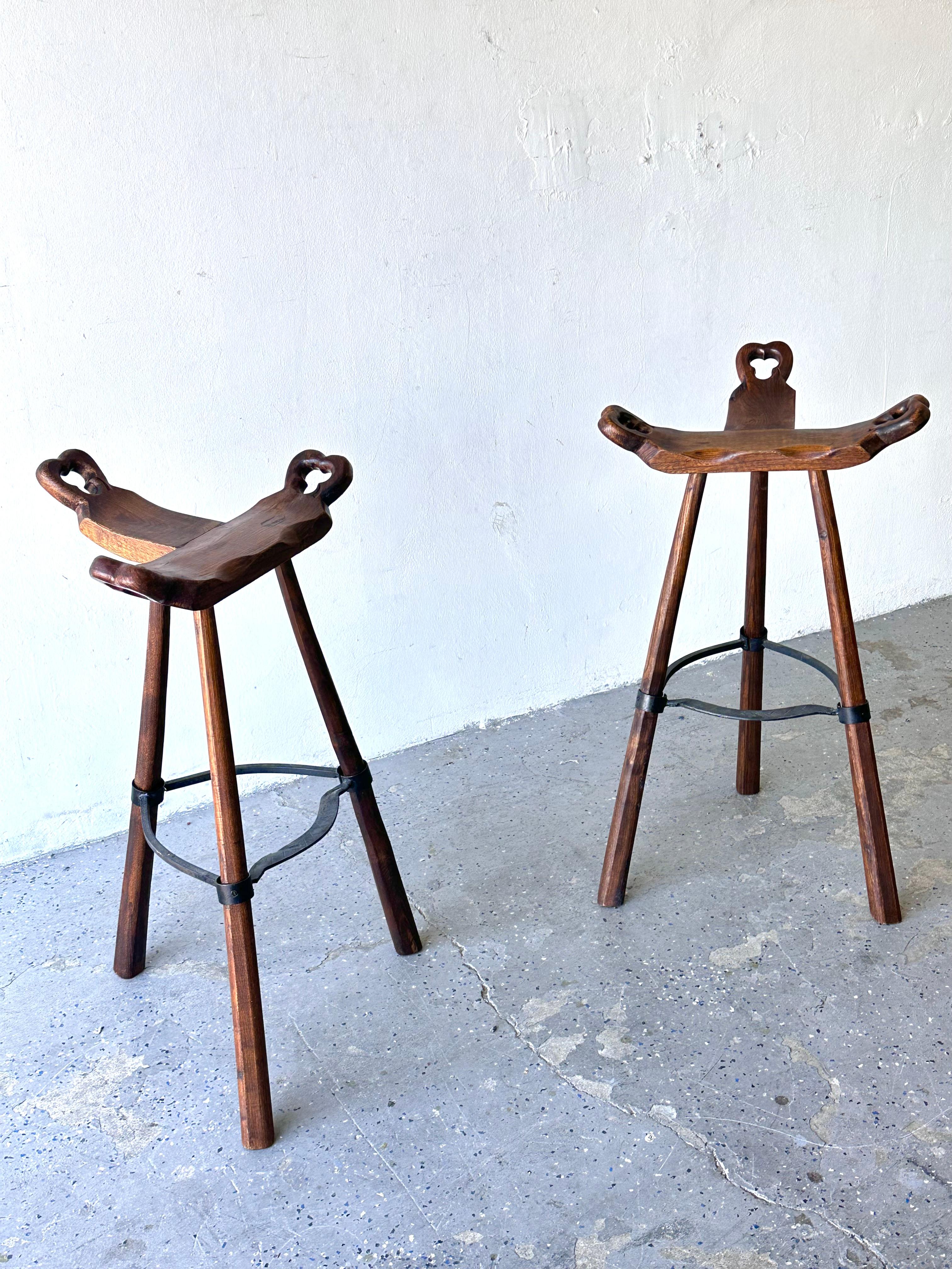 These tripod-base Sergio Rodrigues style bar stools are unique and stunning! Their seats are inspired by primitive birthing chairs. Hand-hammered iron with brutalist texture, and gorgeous wood legs and seats. 

Features:

Seats are inspired by