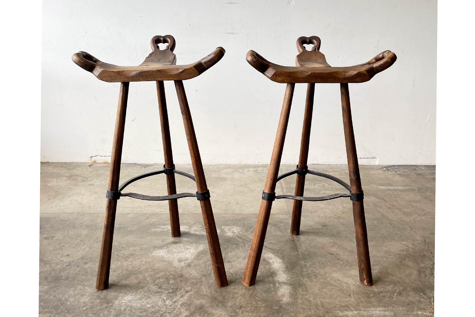 These tripod-base Sergio Rodrigues style bar stools are unique and stunning! Their seats are inspired by primitive birthing chairs. Hand-hammered iron with brutalist texture, and gorgeous wood legs and seats. 

Features:

Beautifully patinated
Seats