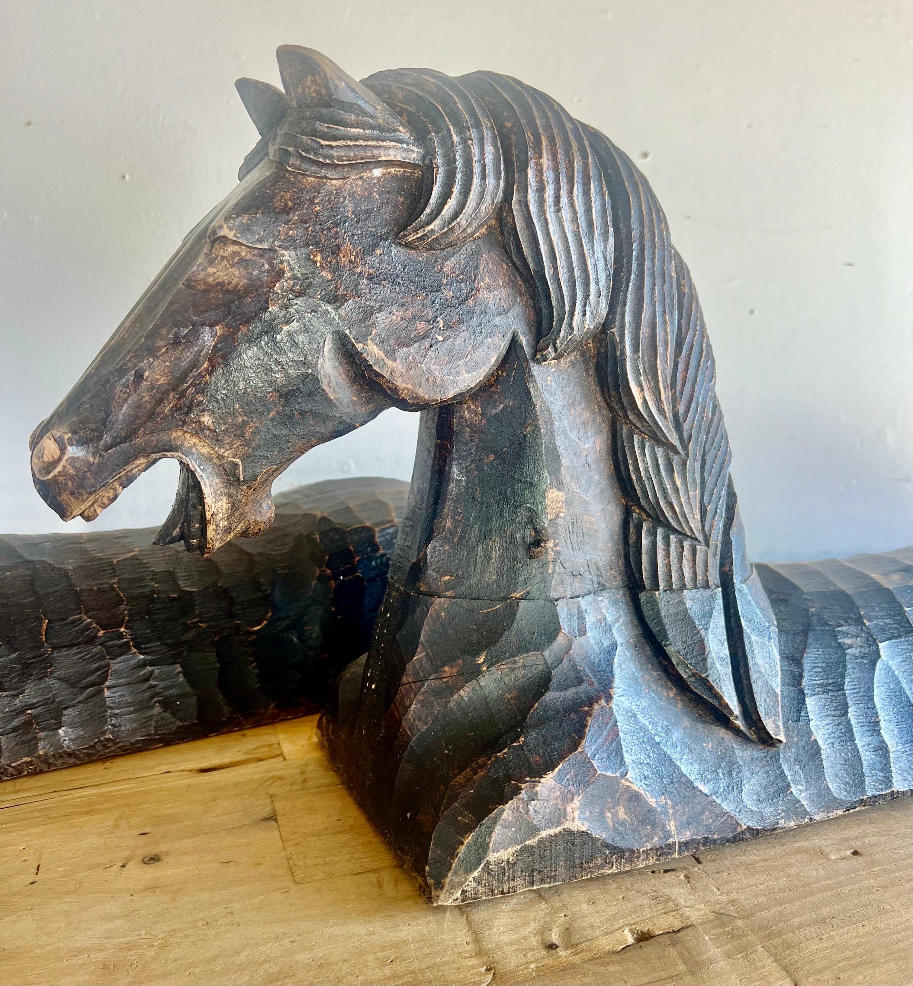 Deux sculptures de chevaux ciselées à la main, à l'esthétique primitive.  Leur finition altérée par les intempéries leur confère du caractère et leur confère un caractère historique.  Placés sur le manteau de la cheminée, ils peuvent servir de