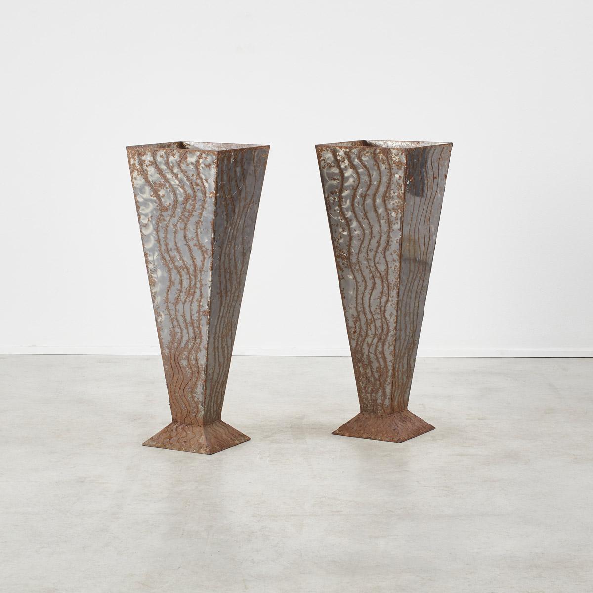 Standing to attention, this pair of artisanal steel planters have a brutalist feel to them and are a striking accessory to any entrance. Their surfaces are covered in wave-like markings which over time have allowed the surface to develop a pleasing