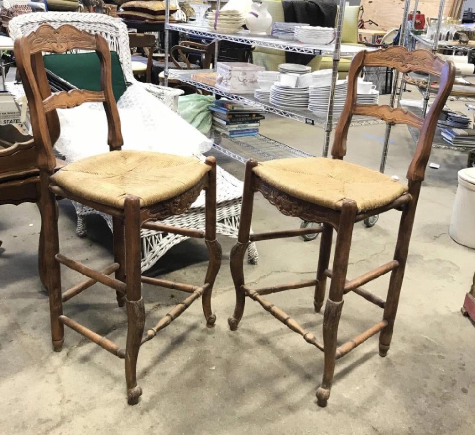 Pair of French Louis XV Provincial style carved wooden bar stools with rushed seats and cabriole style front legs.  Rush shows wear.
