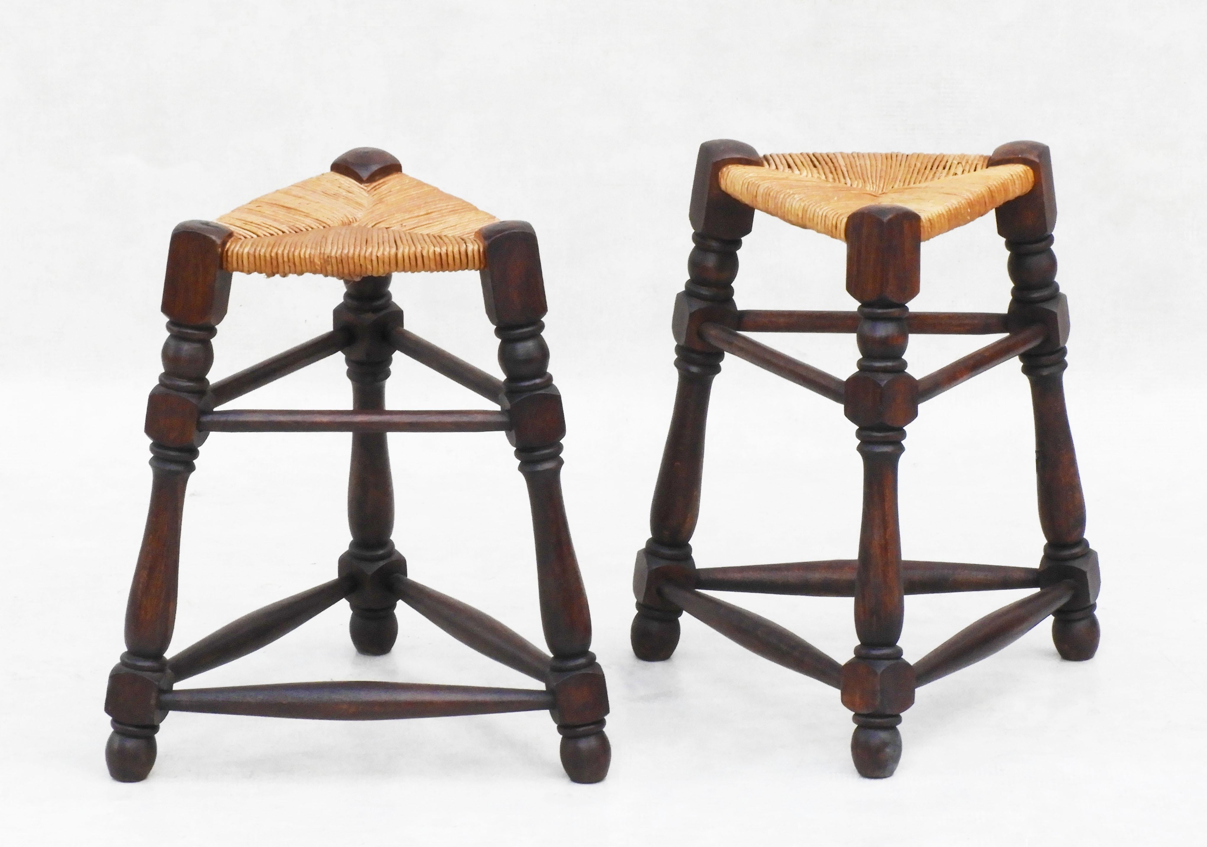 Ein gutes Paar dreieckiger französischer Provinzialhocker aus der Jahrhundertmitte, um 1950. 
Handgeflochtener Binsen-Sitz auf einem gedrechselten, dreieckigen Holzrahmen. 
Die Quintessenz des traditionellen französischen Provinzialdesigns. 
In