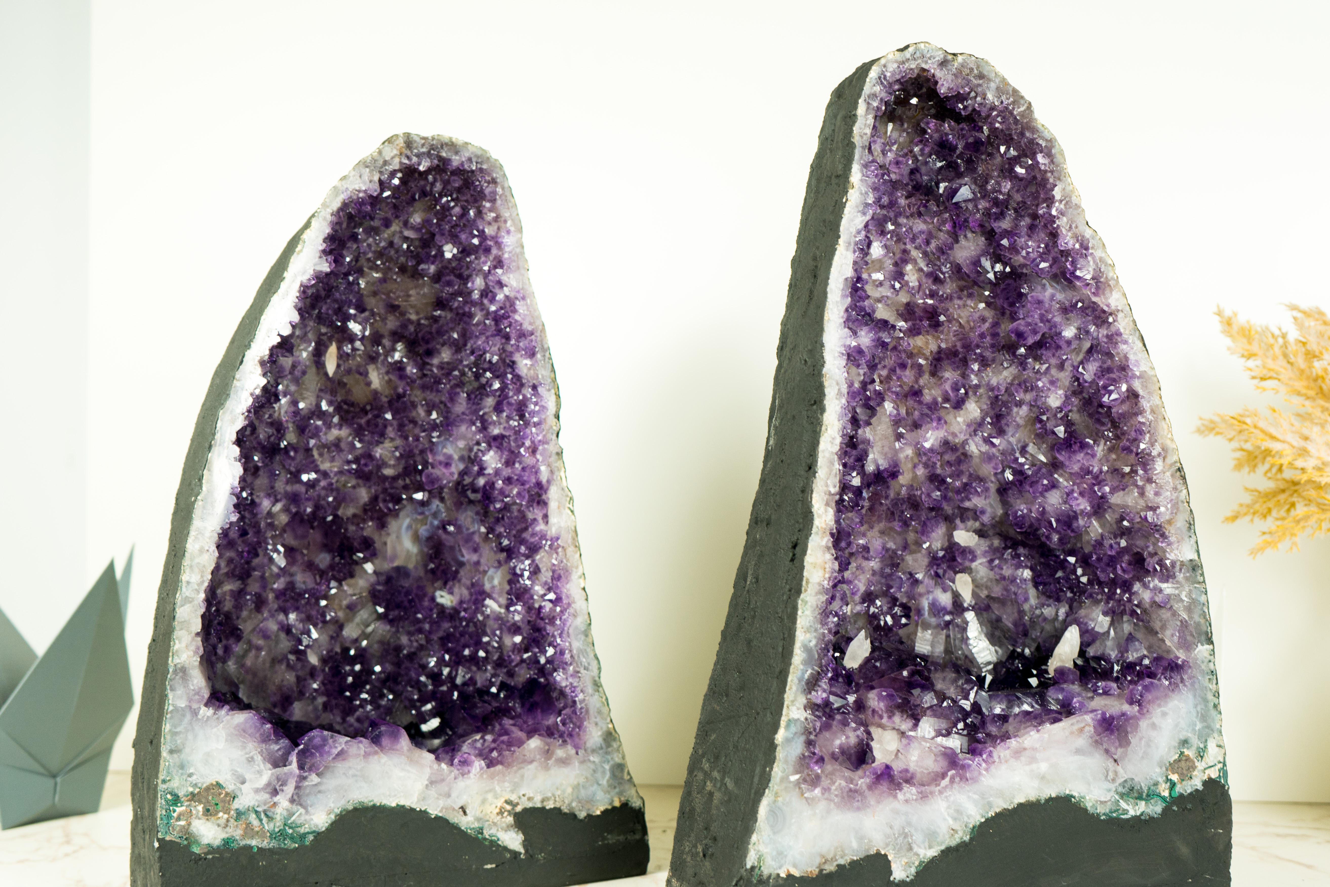 A pair of Amethyst Geodes, each bringing the rarely seen dual-zoned purple Amethyst druzy, gorgeous aesthetics, and rare calcite inclusions, are pieces of natural artistry. These geodes are centerpieces that will elevate your home or office decor to