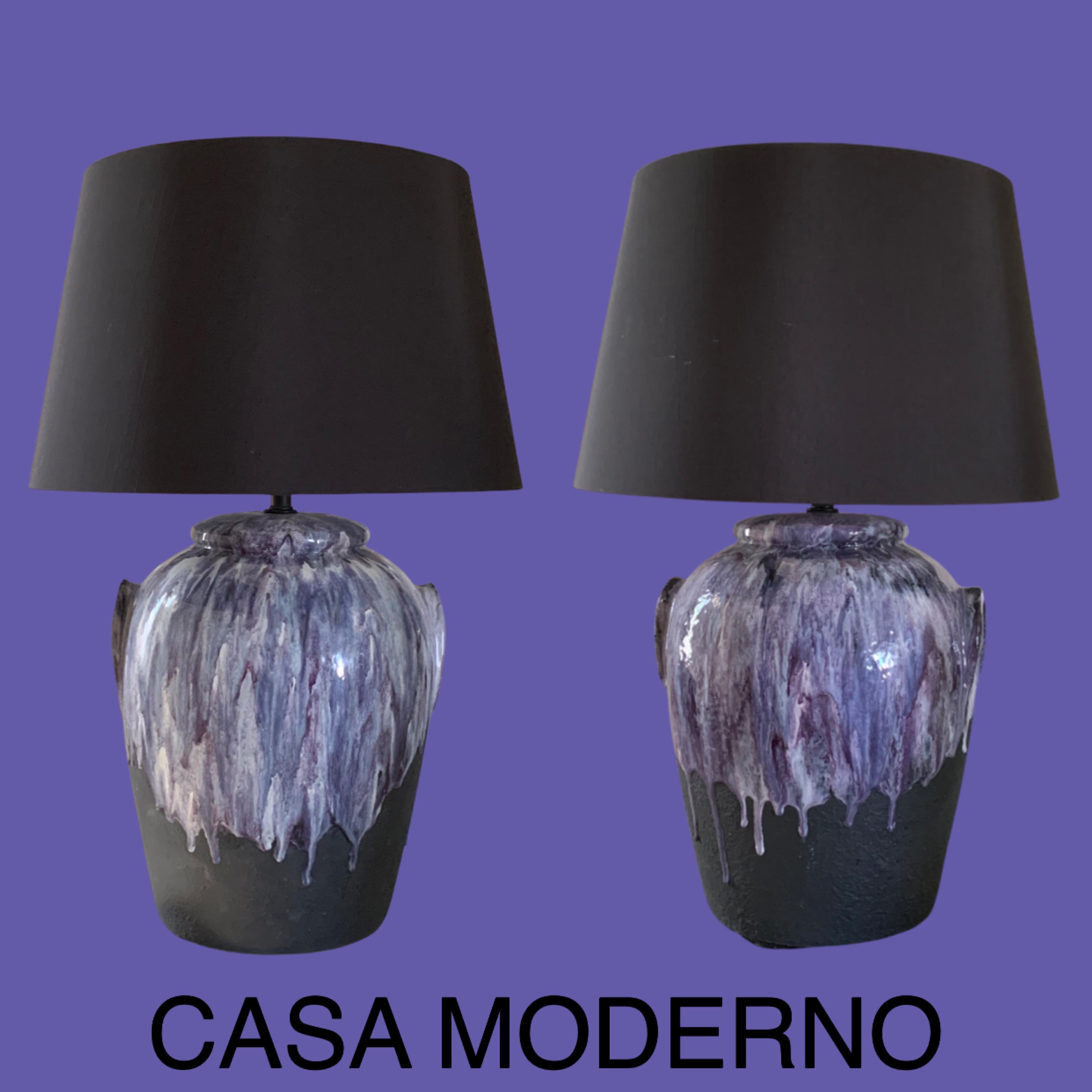 Pair of beautiful modern ceramic lamps from a Palm Springs estate. The lamps have ceramic black bases with an amazing multi shades of purple drip glaze. Beautifully done by the artist in firing the glaze. Decorative jar faux handles on sides. Custom