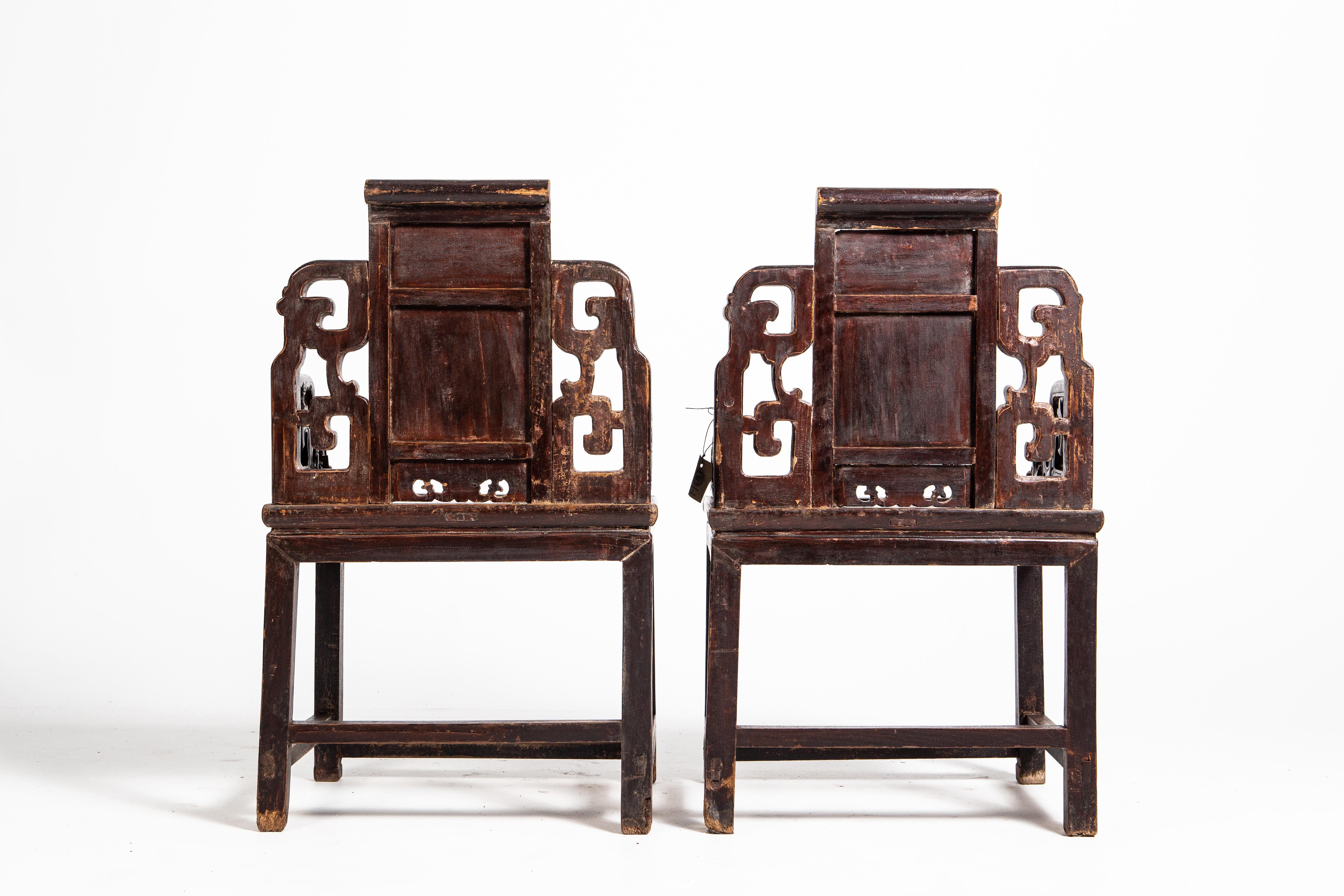 These handsome chairs feature floral carvings, delicate scroll-work on their apron and steeped arms. Made during the Qing Dynasty the chairs are made up of two parts: a waisted stool and an upper backrest that resembles a screen panel. Stout and