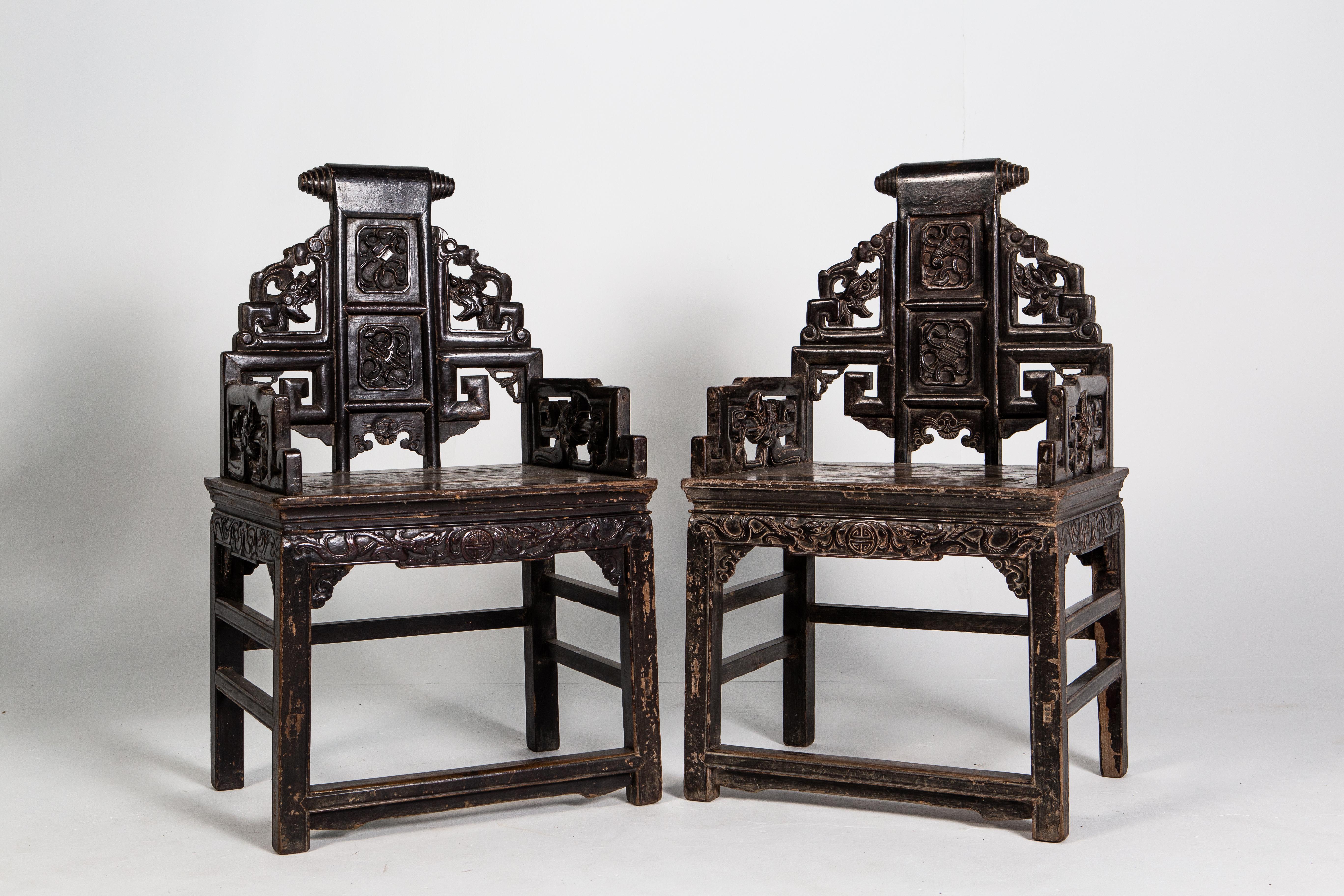 These handsome chairs feature intricate carvings depicting dragons, steeped arms and an ornate scroll on its crest rail. Made from the Qing dynasty, the chairs are made up of two parts: a waisted stool and an upper backrest that resembles a screen