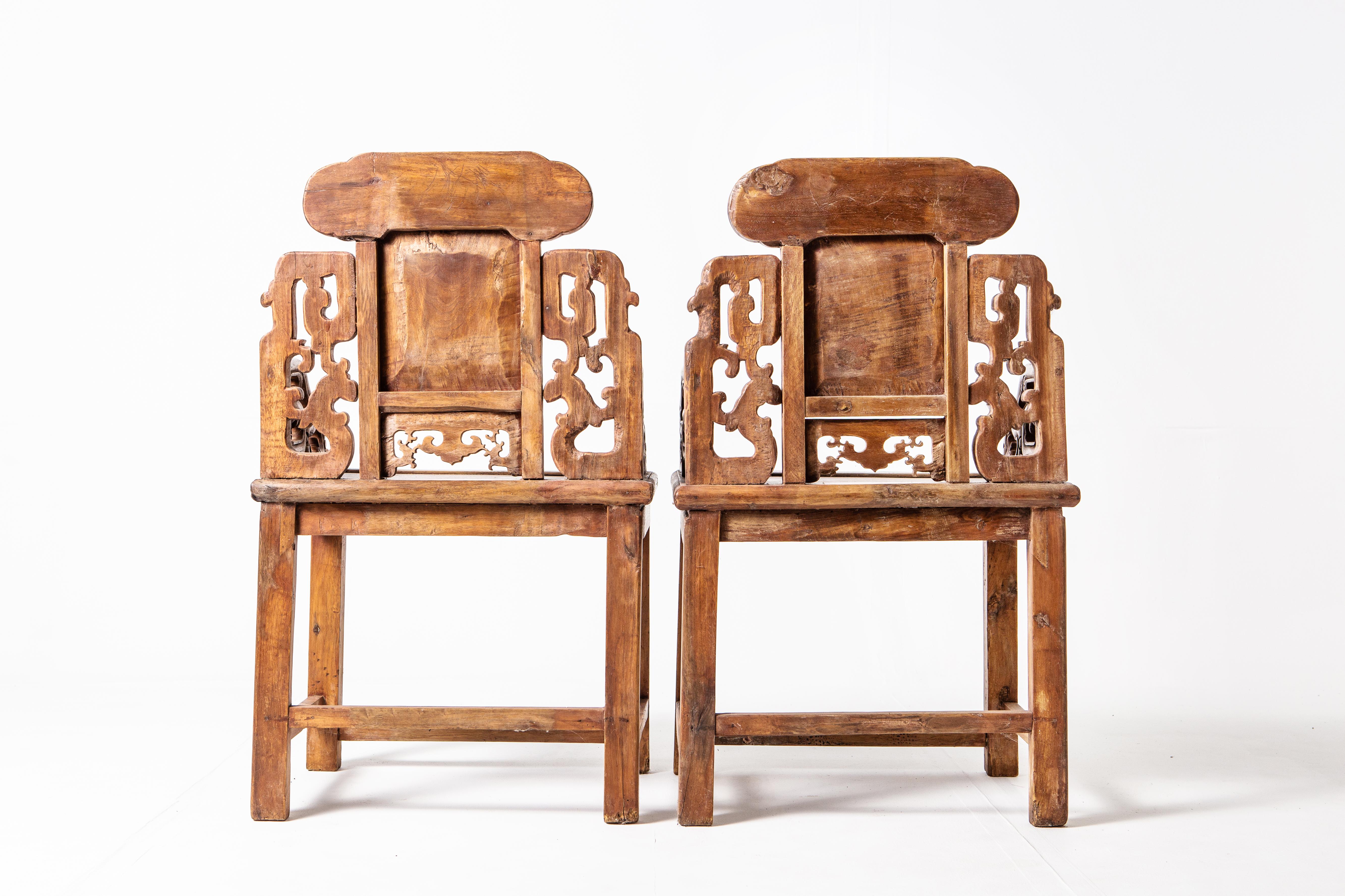 This beautiful and exquisitely carved pair of armchairs is from Szechuan Province, China and date to the middle-Qing dynasty. The frame of each back is in the form of a stylized archaistic dragon. The upper back suggests a cloud motif or auspicious
