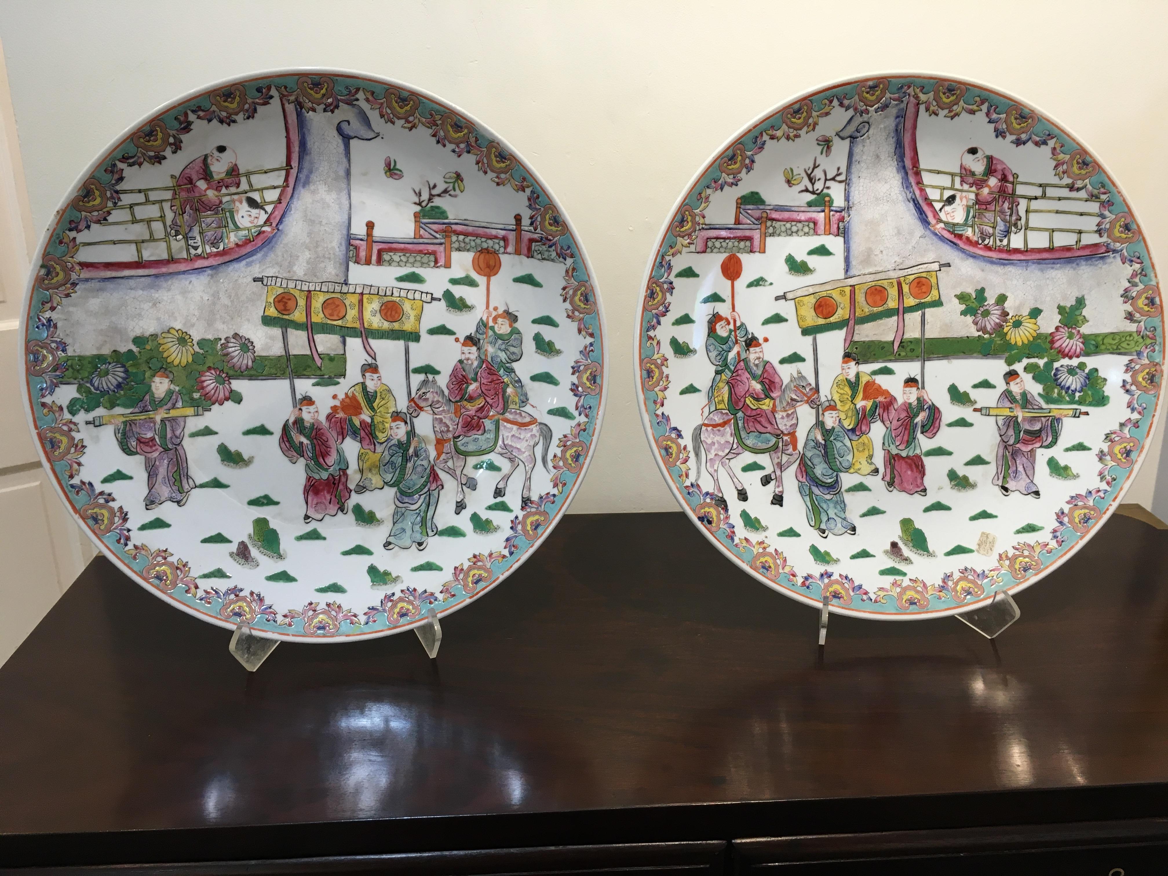 Very rare to find a true pair of Famille rose porcelain chargers. Look closely, there is a left hand view and right hand view. Scene depicts an important arrival complete with entourage and onlookers. Butterflies on the underside with markings. In
