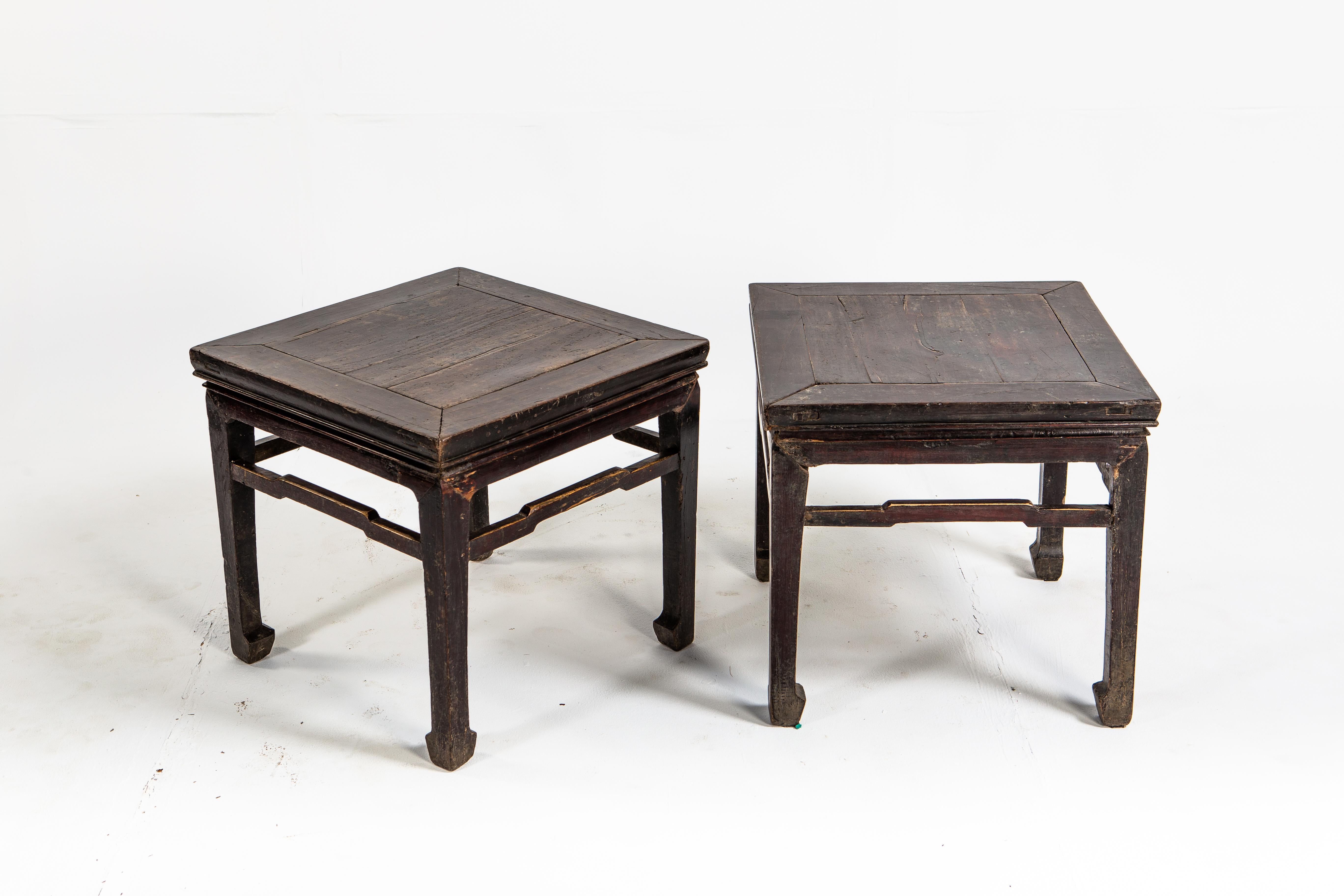 This pair of square-waisted stools are from Shanxi, China and made from elmwood The stools feature humpback stretchers and horse hoof legs. Dating back to the late Qing dynasty the stools were once covered in ox blood lacquer.
