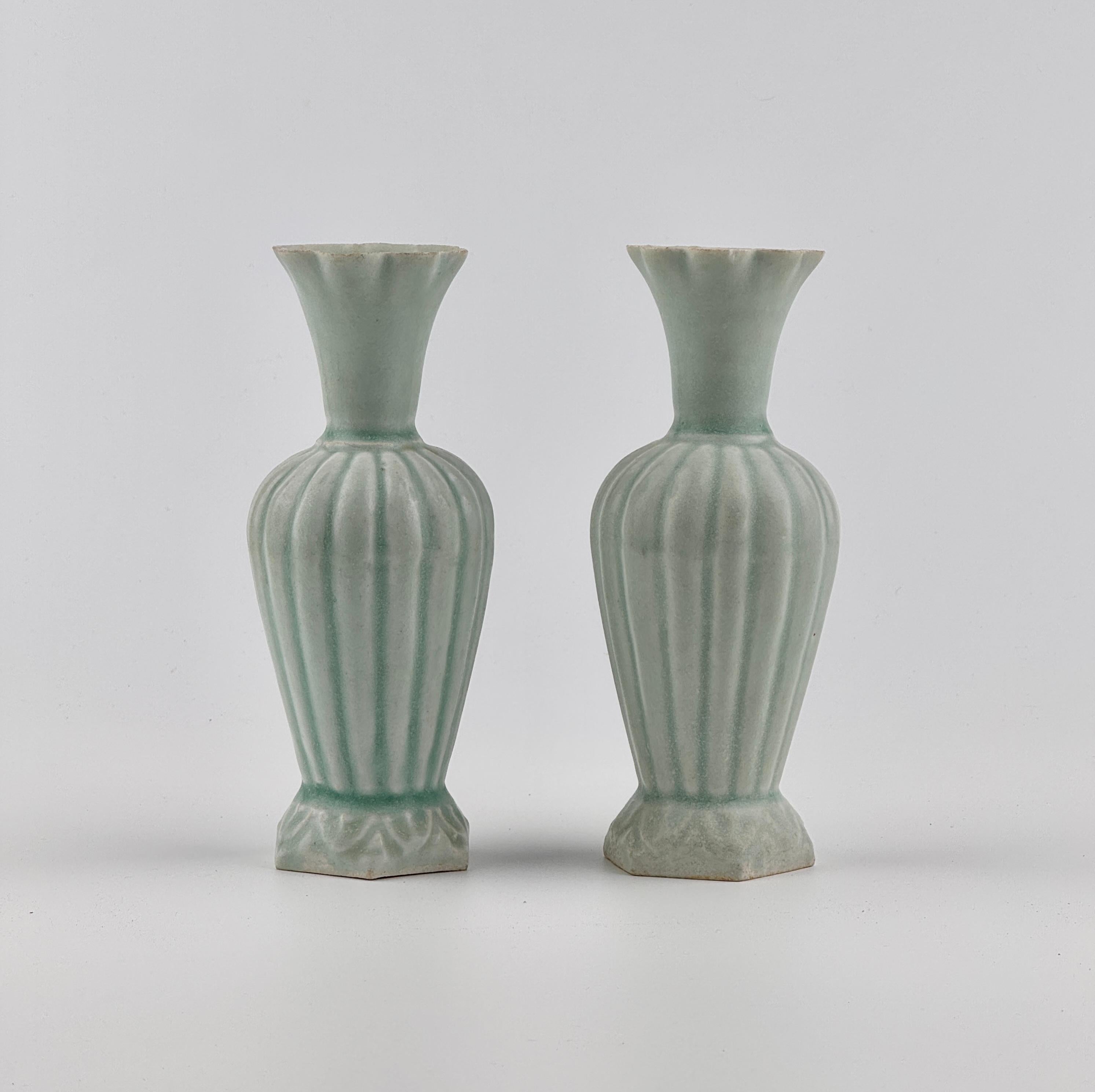 Questa coppia di vasi Qingbai presenta un morbido smalto verde-bluastro con eleganti corpi scanalati e ampi bordi svasati. I vasi sono realizzati a mano, con sottili differenze che ne evidenziano la natura artigianale. La base non è smaltata e, se