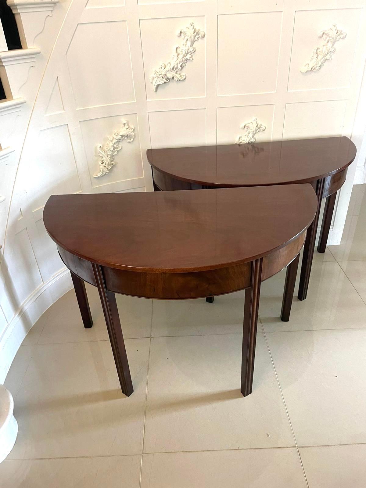 Pareja de consolas antiguas Jorge III de caoba labrada de calidad, con tablero de caoba labrada de calidad en forma de demi lune, sobre un friso de caoba con borde acanalado, apoyadas sobre cuatro patas cuadradas, ahusadas y reed.

Una bonita pareja