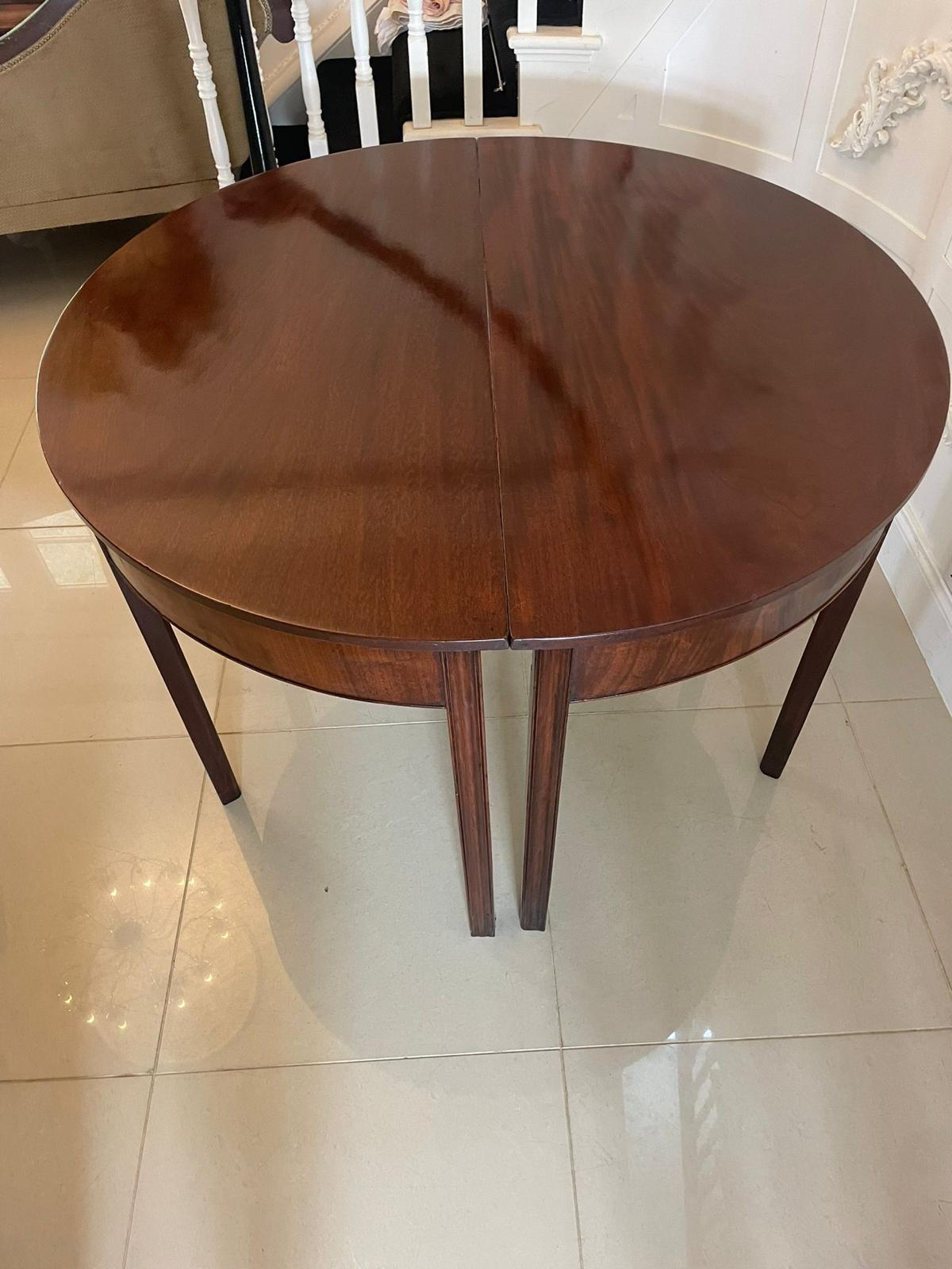 Pair of quality figured mahogany antique George III demi lune console tables having a quality figured mahogany demi lune shaped top above a mahogany frieze with a cockbeeded edge standing on four square reeded tapering legs

A handsome 18th century