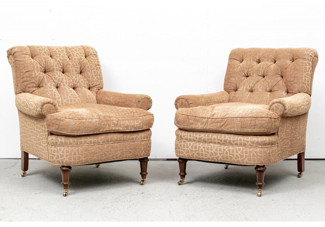 Very well made and stylish club chairs with rolled crest rails and arms, button tufted backs and comfortable seat cushions. With deep curved seat rails raised on turned front legs on casters, and square splayed back legs. Great upholstery in a tan