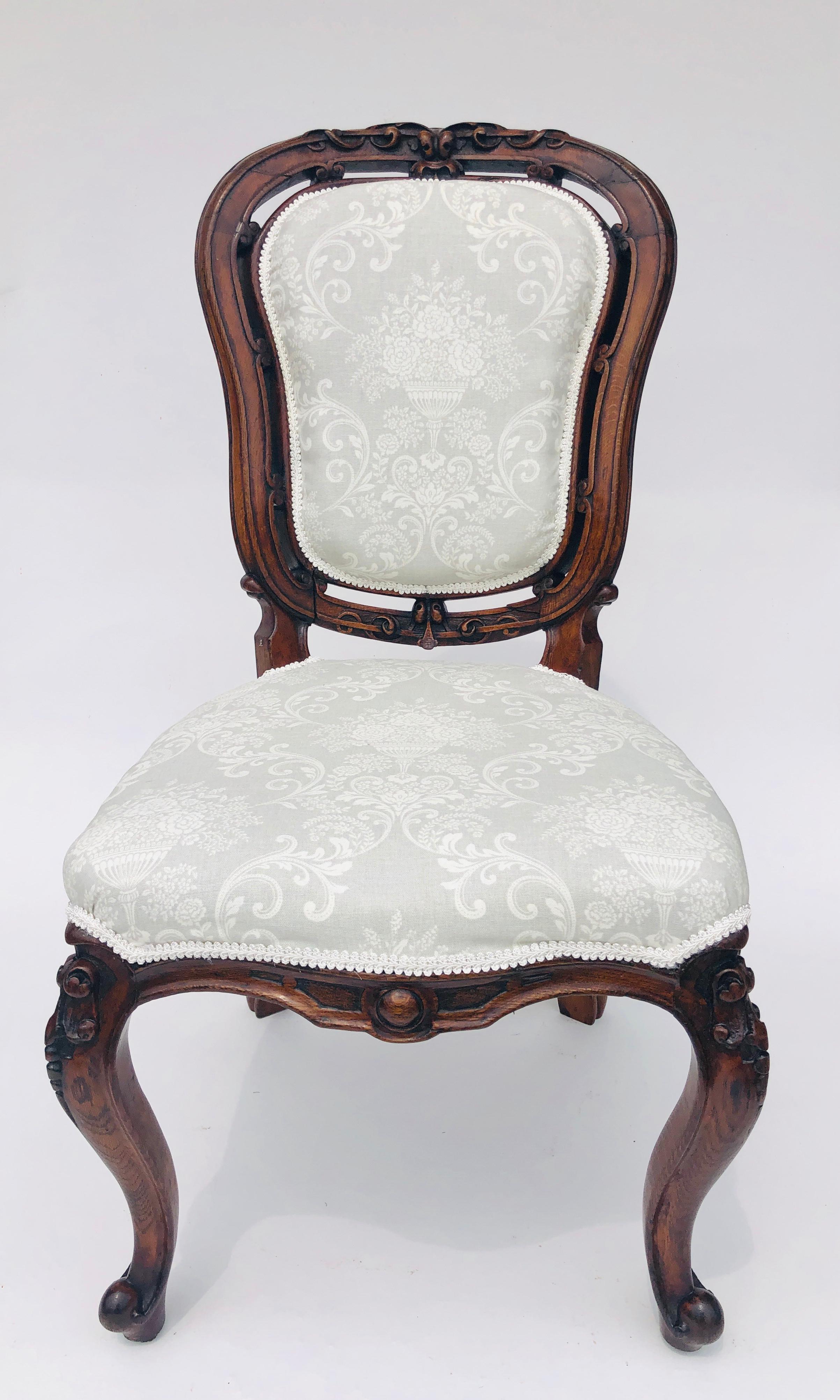 Pair of quality antique Victorian walnut carved side/desk chairs. These chairs have a beautifully carved shaped back with a carved pierced border. Newly re-upholstered back and seat in quality fabric. Standing on attractive shaped carved cabriole