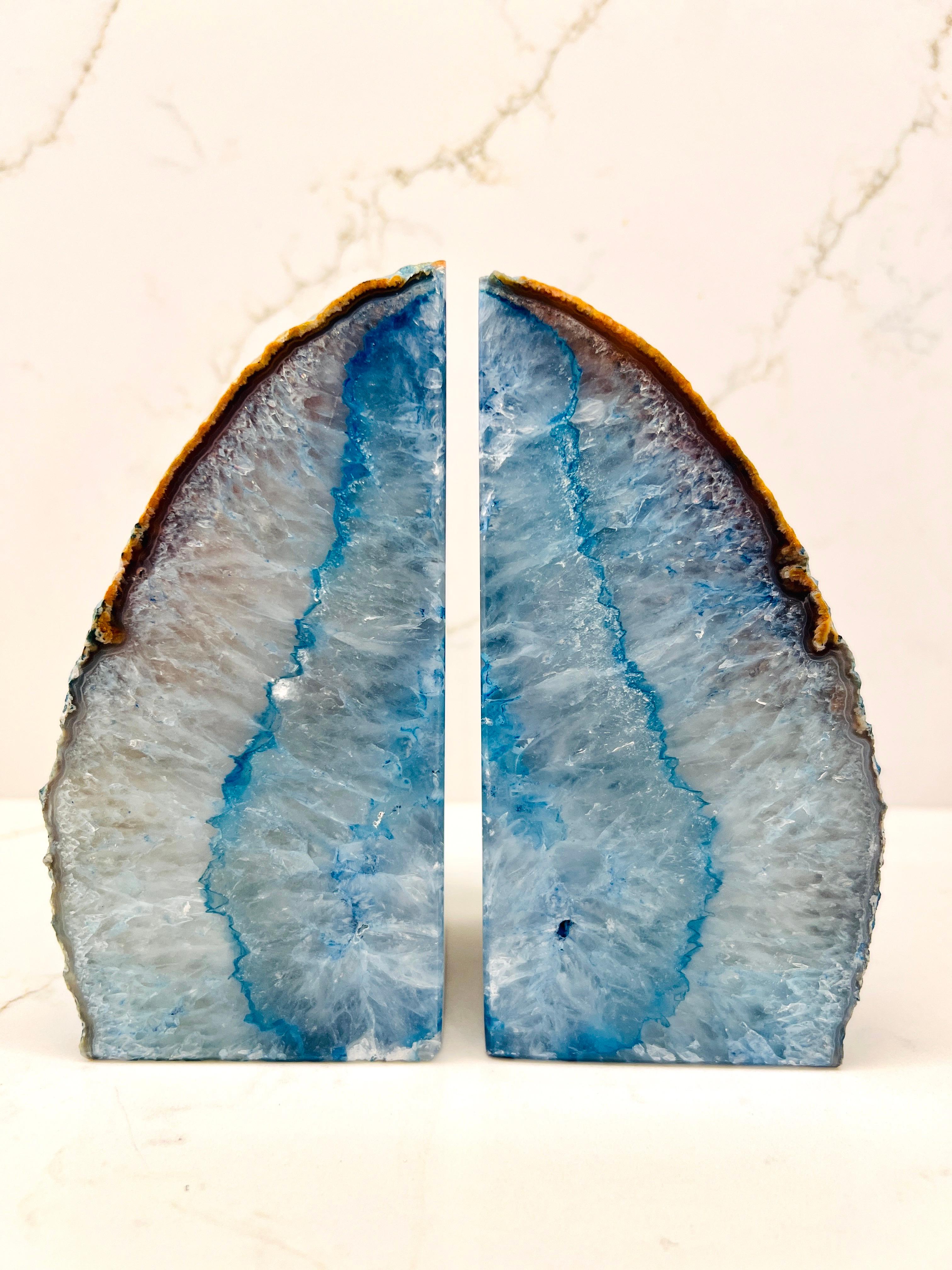 Ein Paar Buchstützen aus natürlichem Quarzkristall mit leuchtenden Blautönen. Die handgeschnitzten Exemplare haben polierte Fronten mit rauen, lebendigen Kanten. Sie bestehen aus kristallisierten Mineralien, die Tausende von Jahren brauchen, um sich