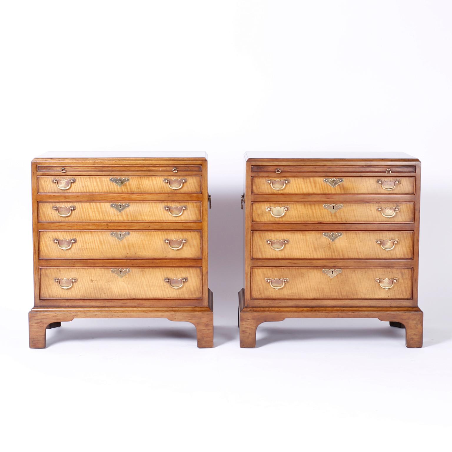 Pair of four drawer nightstands crafted in fruitwood with exotic cross cuts on the drawer fronts and featuring tooled leather slide out trays, floral engraved brass hardware, and classic bracket feet. Signed Beacon Hill in a Drawer.