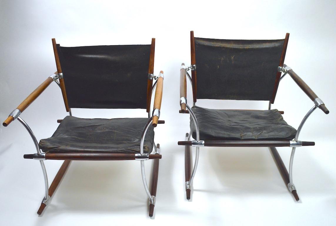 Rare and important pair of Safari chairs designed by Jens Quistgaard for Dansk Danmark. Both chairs are structurally sound and sturdy, both show significant wear to the black leather upholstery, including tears to the back rest slings, as shown.