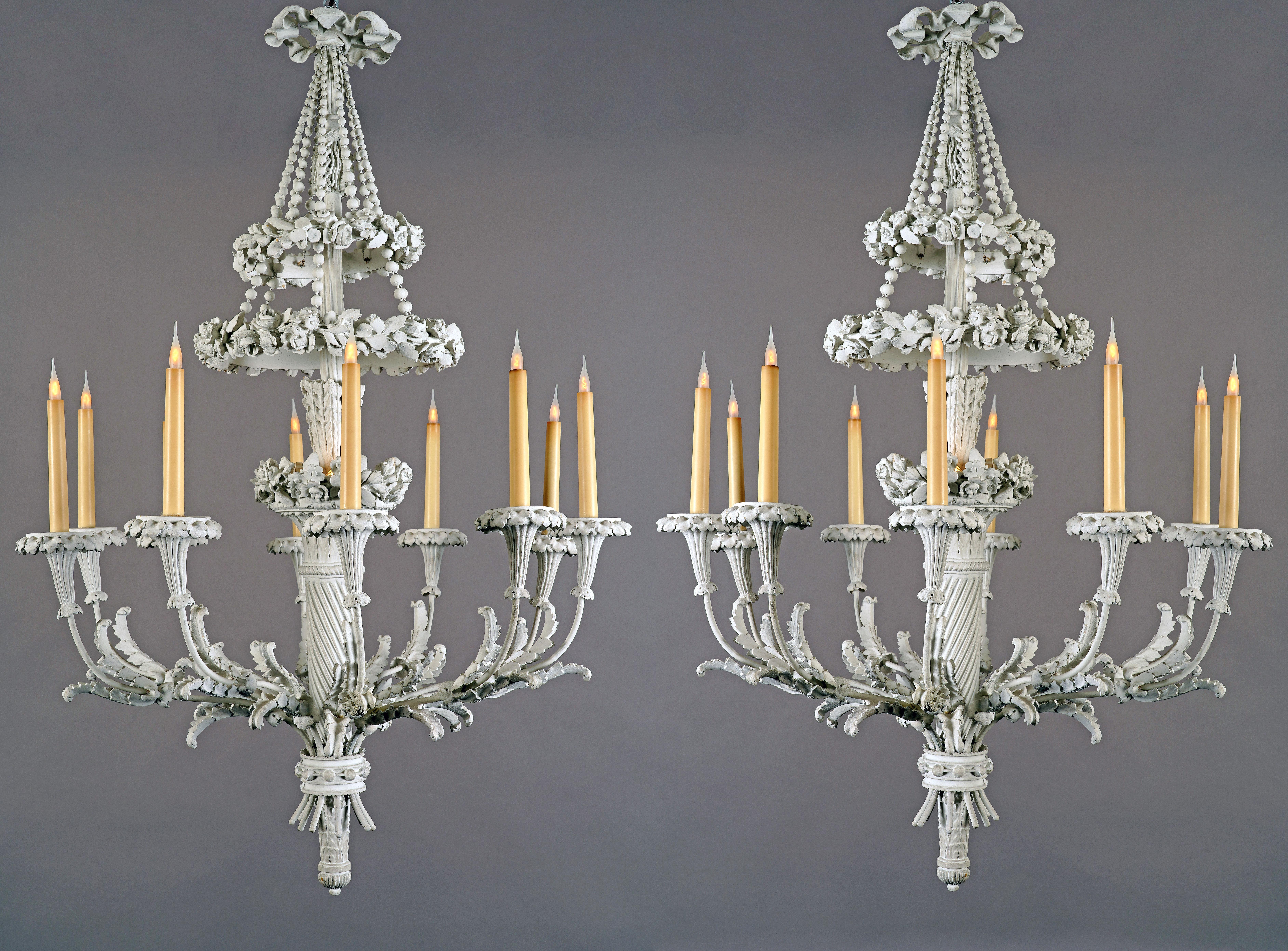 Bellissima coppia di lampadari in stile Luigi XVI, realizzati a mano  stucco e rame con dieci luci. Il fusto centrale a luce indiretta è formato da una faretra decorata con fiori, attorno alla quale un anello di perle riunisce i bracci luminosi a