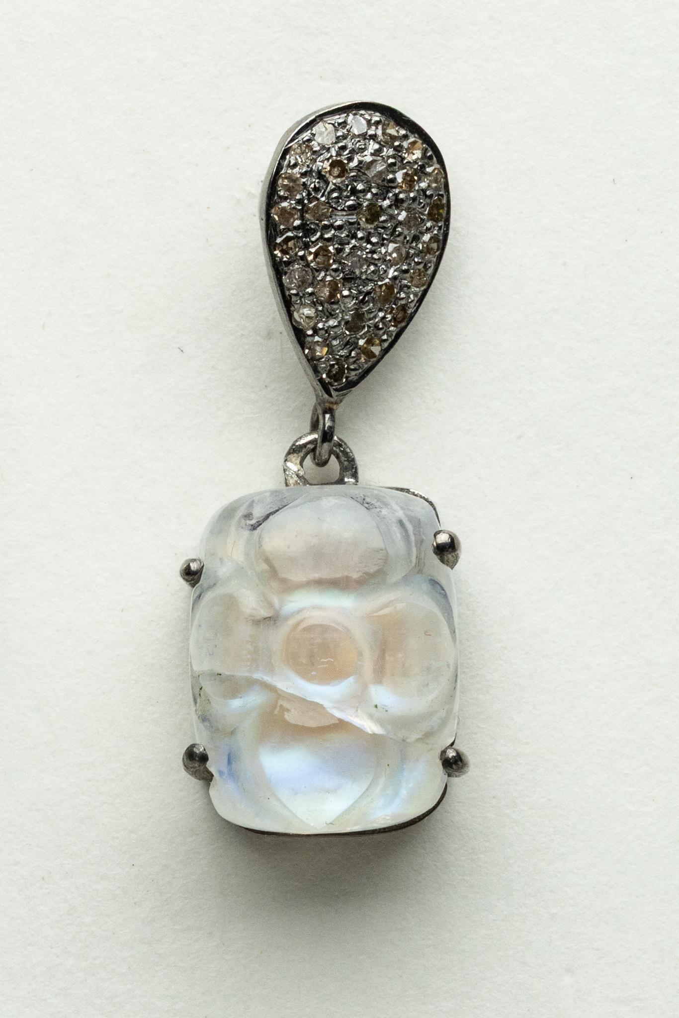 Ein Paar Tropfenohrringe aus Regenbogenmondstein mit einem geschnitzten Blumenmuster auf der Oberseite des rechteckigen Cabochons.  Der Pfosten ist tropfenförmig und mit Brillanten in einer Pave-Fassung aus Sterlingsilber besetzt.  Der Pfosten ist