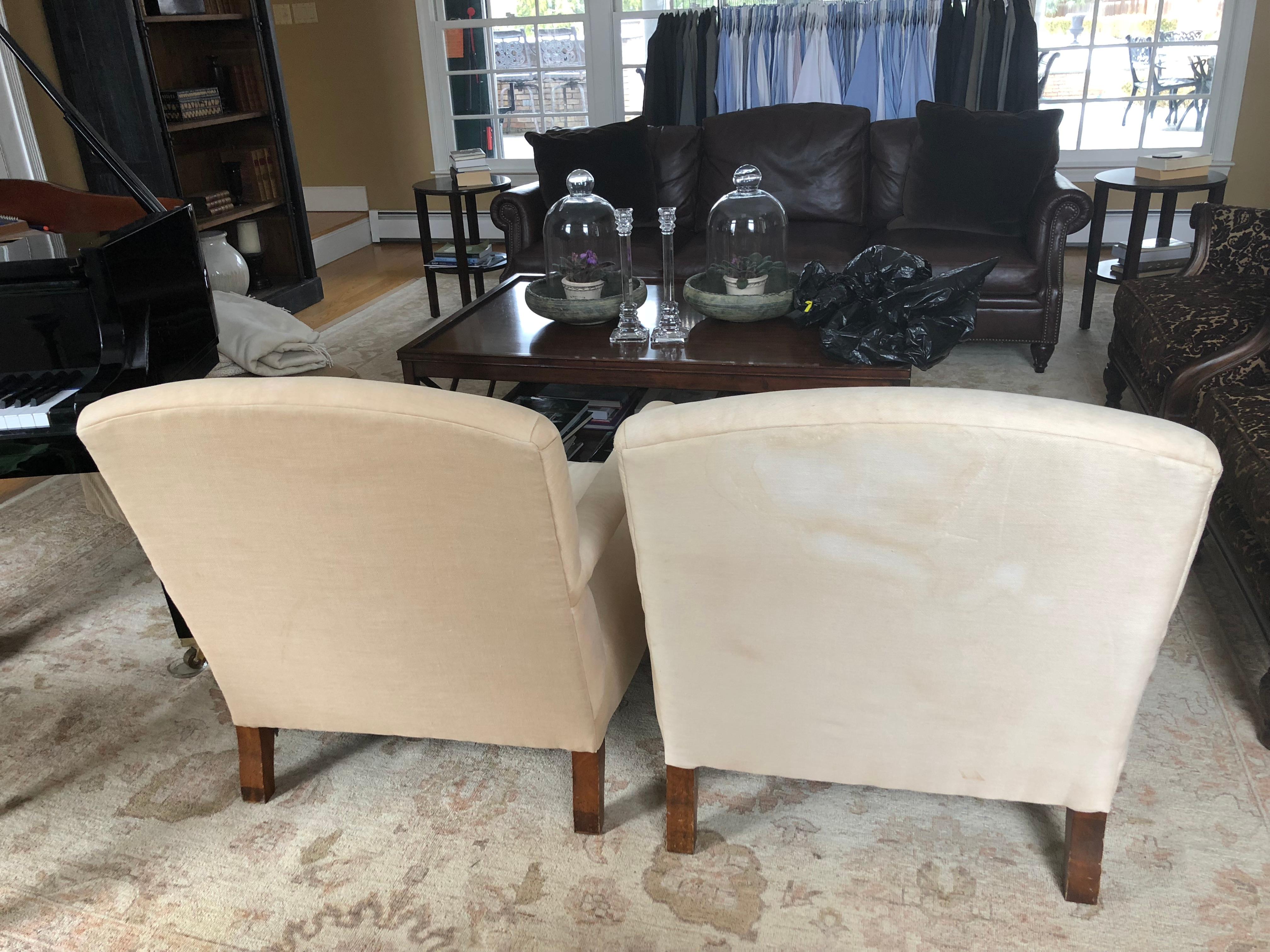 Classic pair of English style library club chairs by Ralph Lauren having walnut arms and legs with brass casters. The style is called Oliver. The original off-white linen blend fabric needs to be replaced as there are stains and wear. But the bones