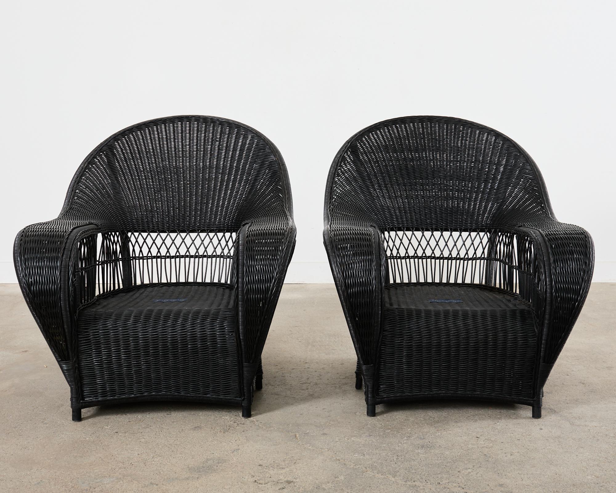 Dramatic pair of ebonized wicker garden lounge armchairs designed by Ralph Lauren. These rare chairs feature an oversized rattan frame embellished with woven wicker. The gracefully curved frames have thick cobra style for backs and wide arms
