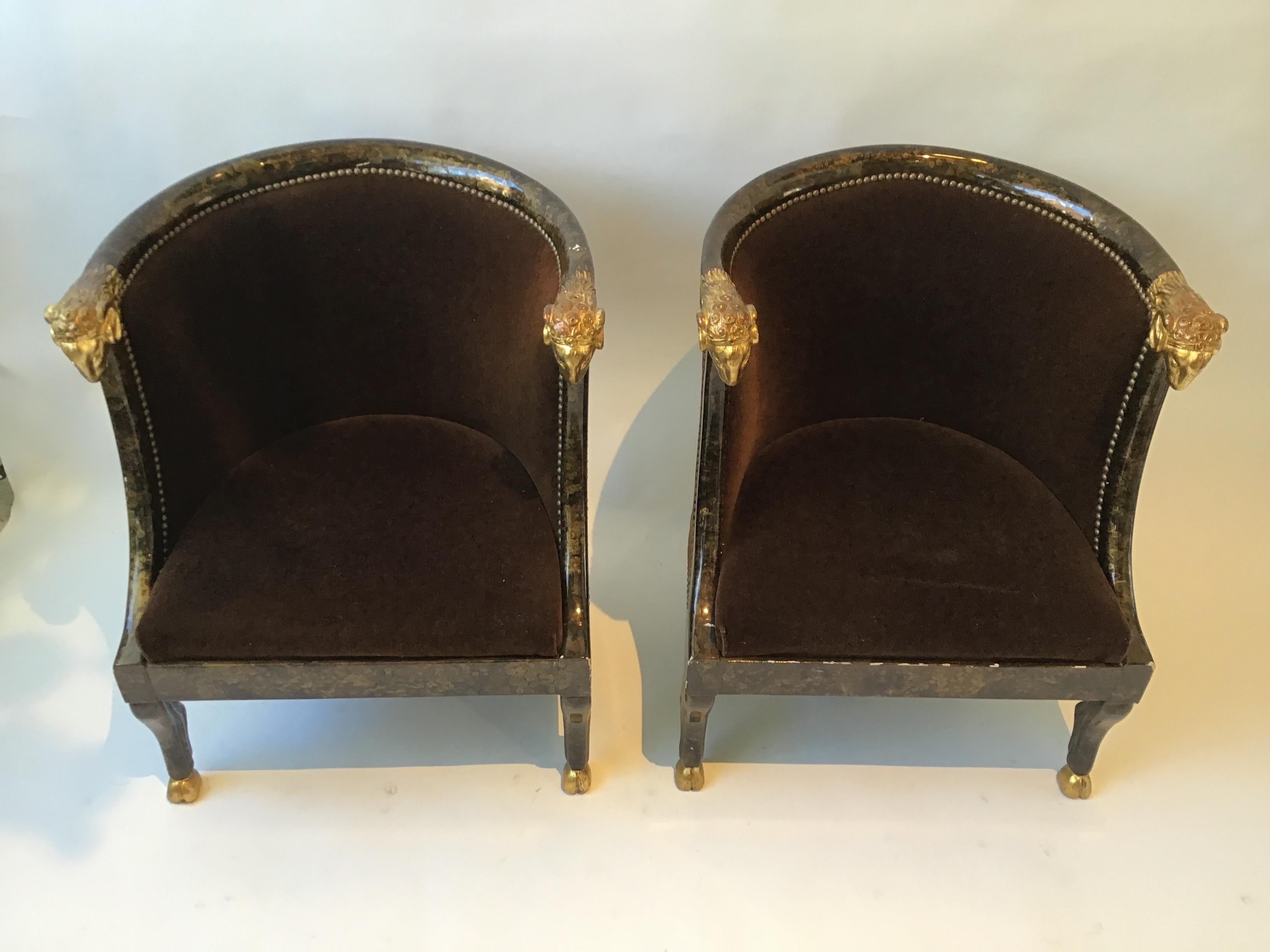 Pair of 1980s carved wood rams head tub chairs. Gilt rams head and feet. Faux painted finish to frame. Some chipping in finish. Brown velvet is about 10 years old.