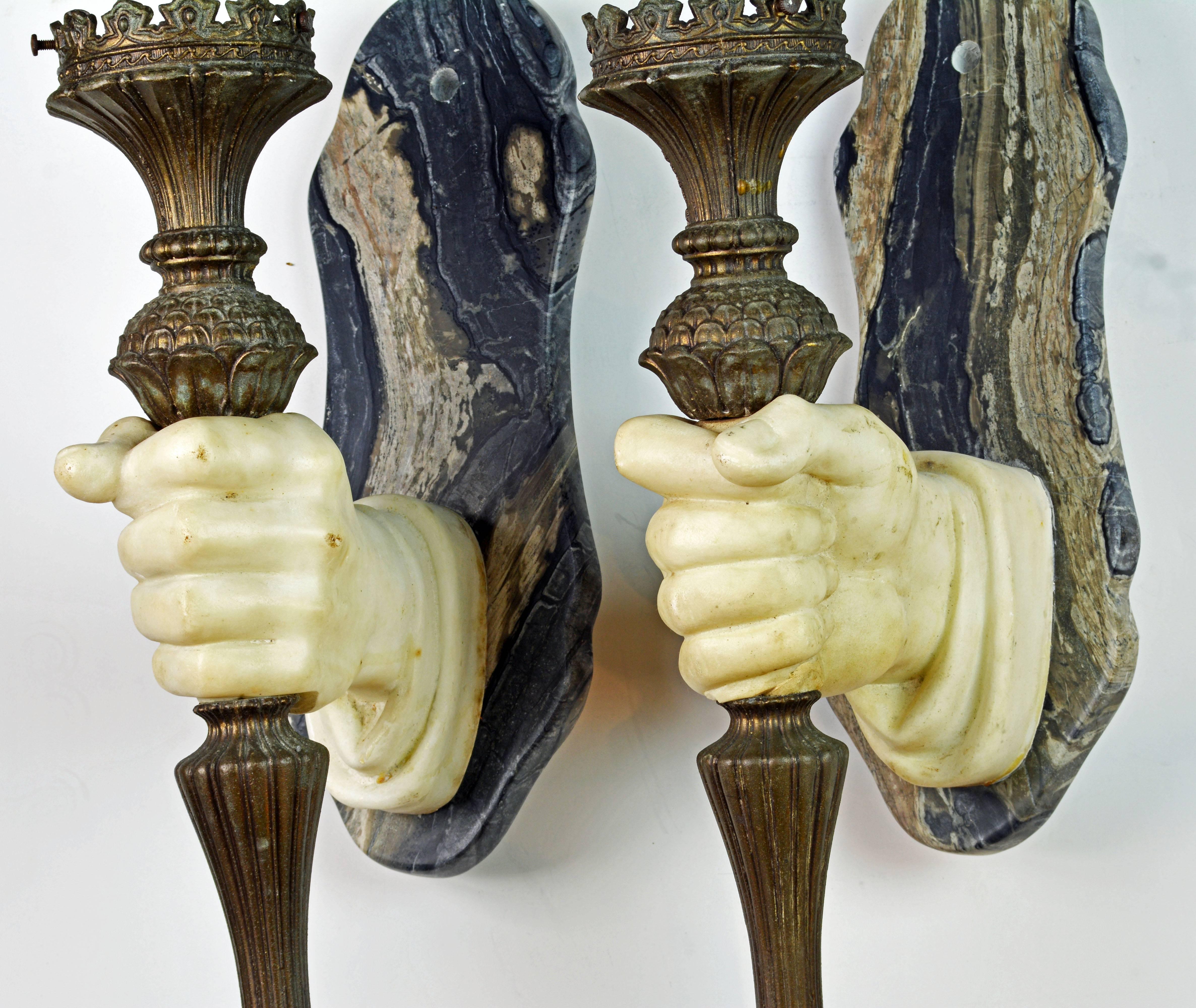 This opposing pair of wall sconces has likely originally been wired for glass globes, see photos. The consist of a marble backplate, one of which has been almost invisible repaired, and two well carved marble hands holding richly decorated patinated