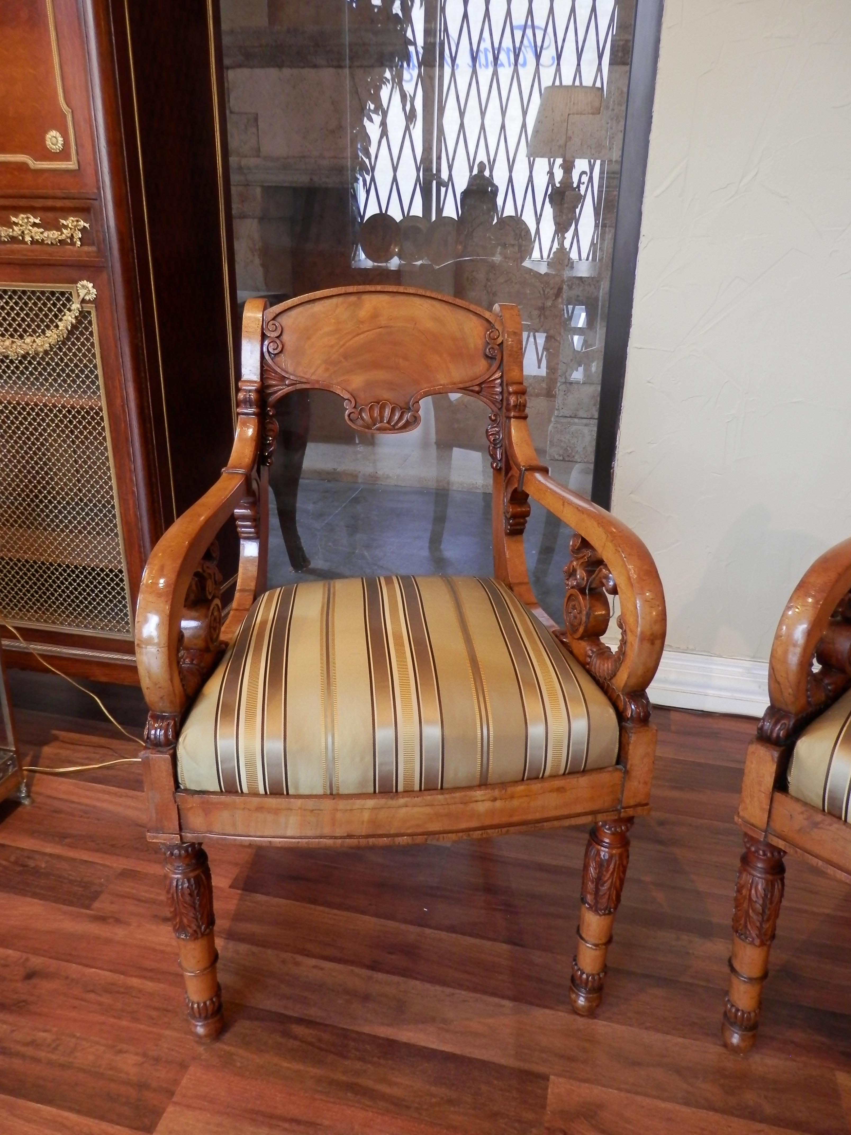 Beautiful and rare pair of early 19th century Baltic walnut carved open arm chairs. The seats are covered in a striped silk material.