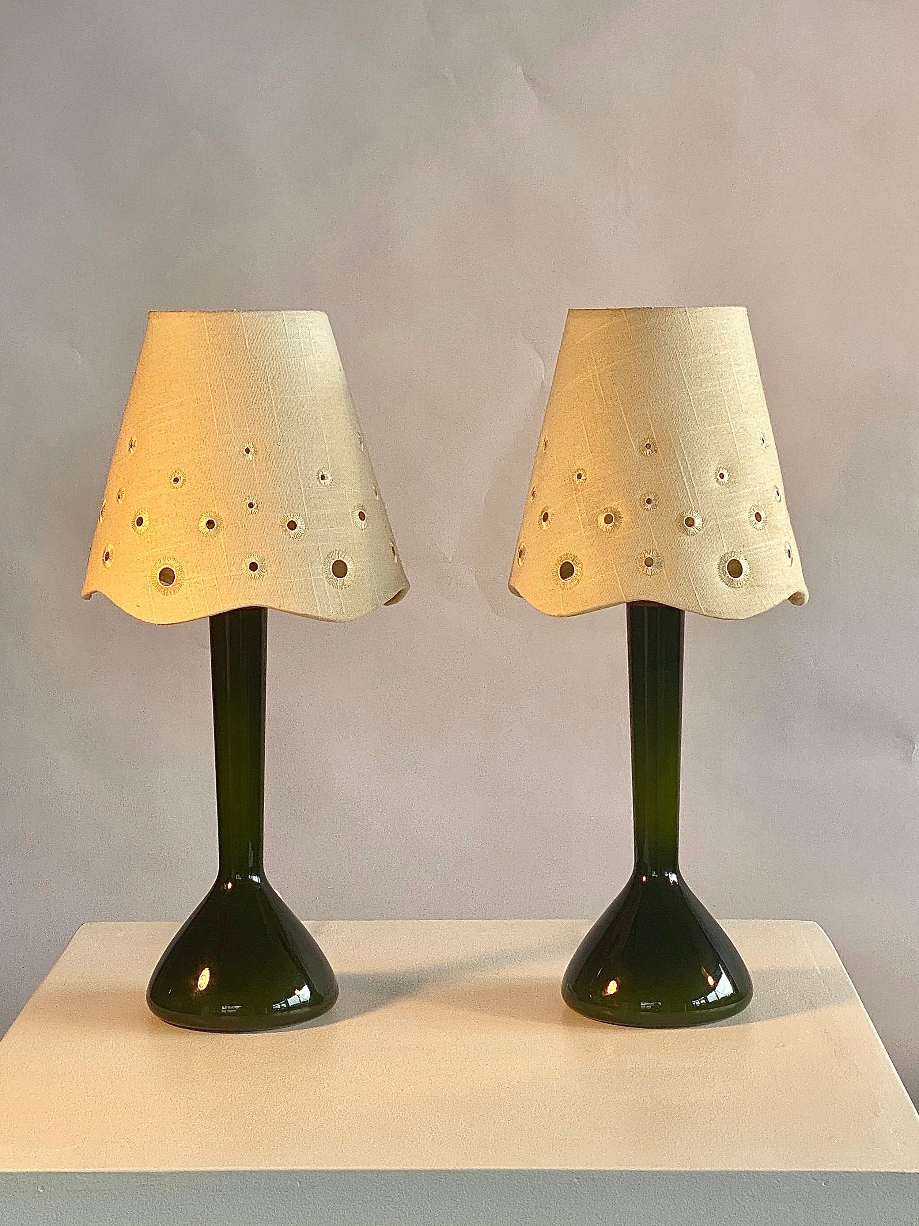Beautiful and rare model dark green hand blown glass pair of lights by Kastrup Holmegaard, Danish design of the 1960s. The shades have round holes in them, which when the lamps are lit in a dark environment, gives a very mystical diffuse light with