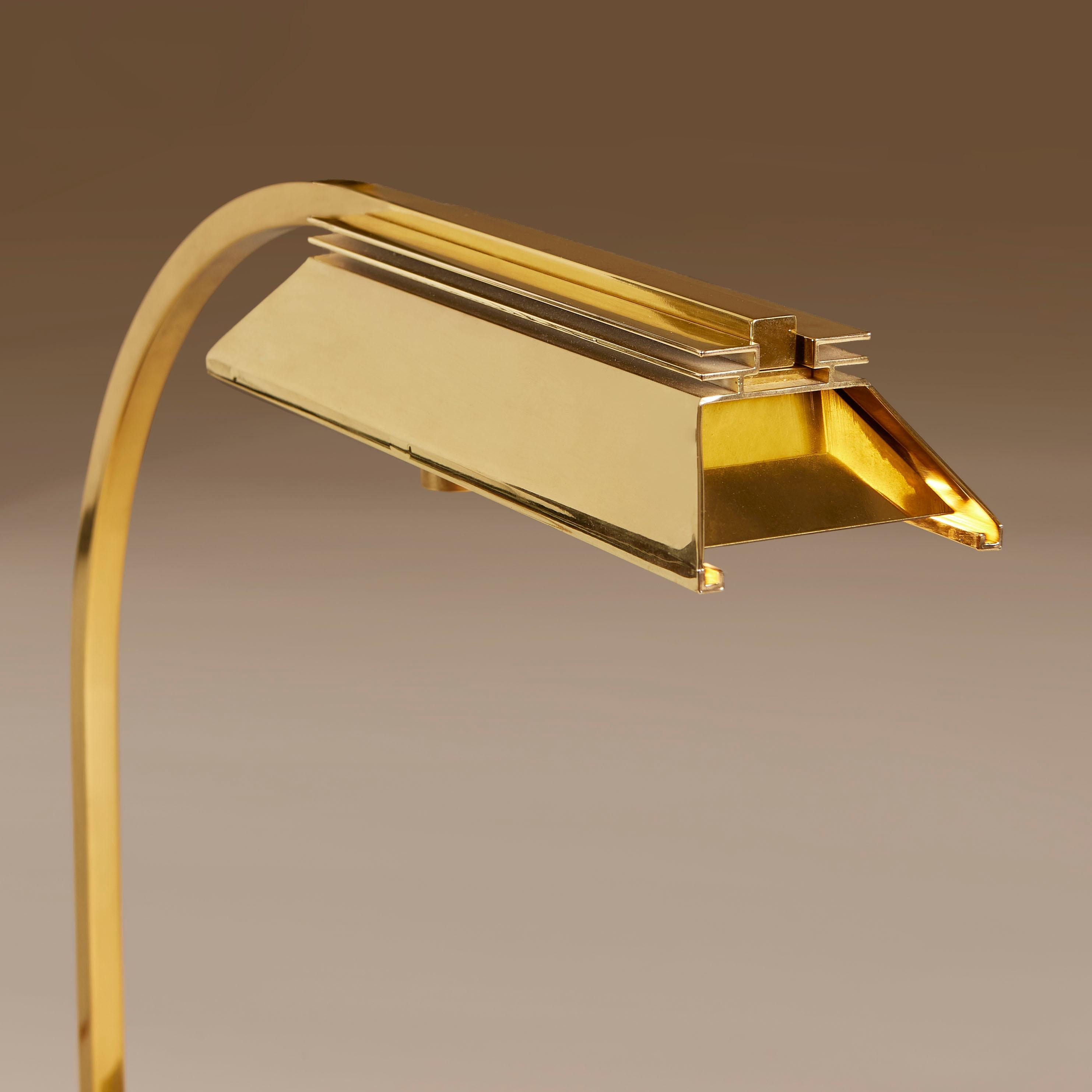 Schicke und massive Schreibtischlampe aus gebürstetem Messing mit dekorativem pfeilförmigem Sockel, gebogenem Arm und dekorativem Messingschirm.

