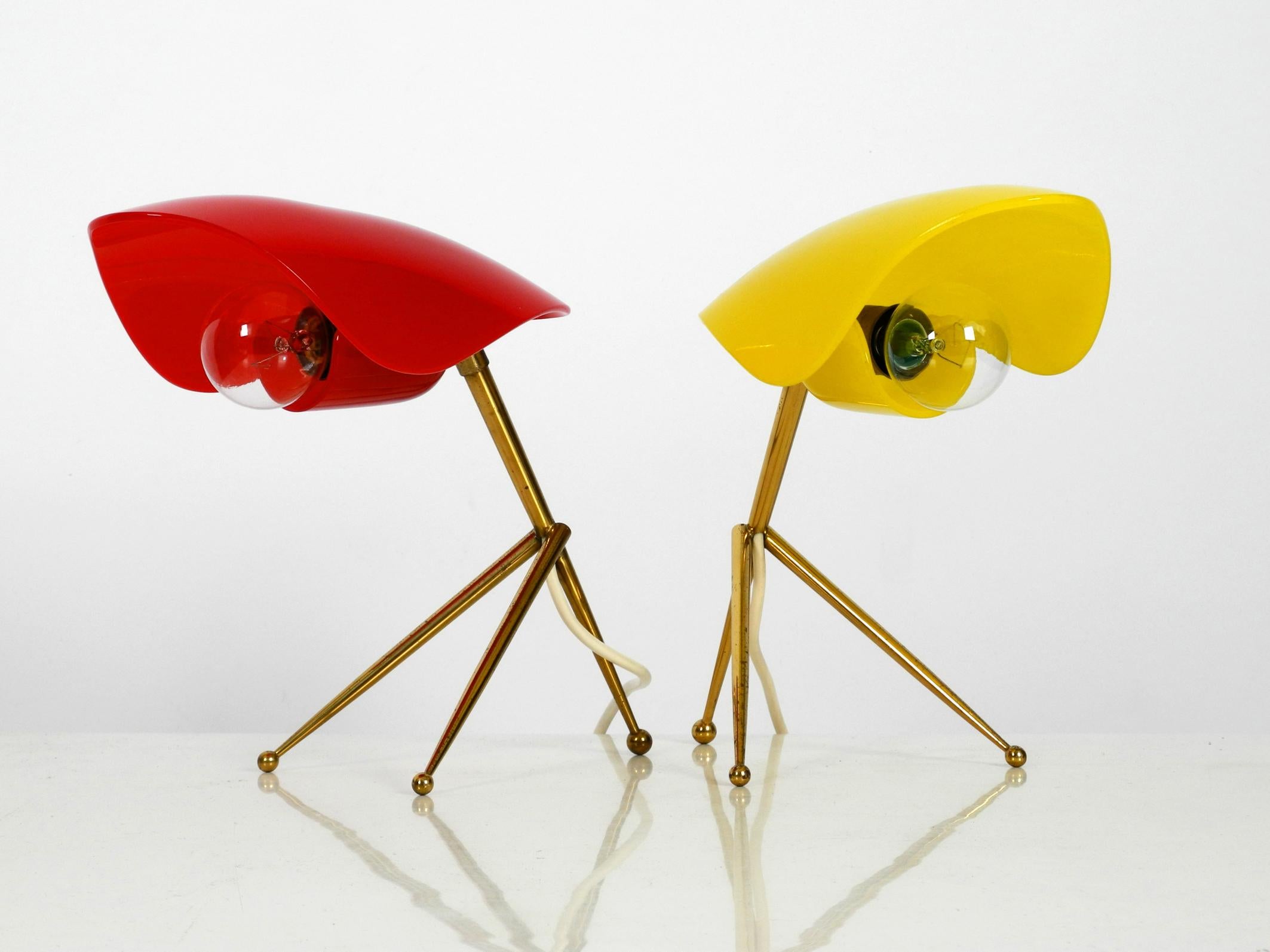 Pair of rare Mid-Century Modern table lamps by WKR Offenbach Germany. 
Lampshades are made of plexiglass one in yellow and one in red and have 
both brass three-legged frames.
Very beautiful 1950s design in very good vintage condition. 
100%