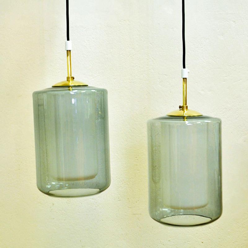 A pair of cylinder shaped and smoke colored ceiling pendants with inner cores of special white glass made by Høvik Lamps, 1965, Norway.
Designed by Jonas Hidle, Norway. Gives a really nice and unique shine and glow of light when lit. Measures of