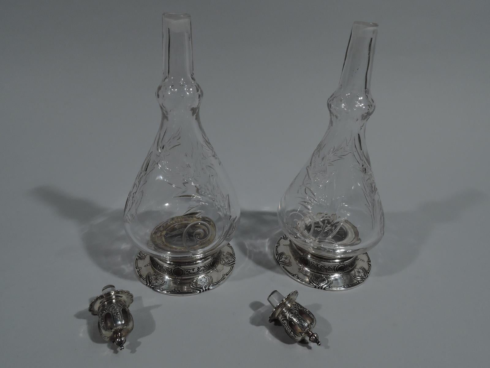 Pair of rare Art Nouveau perfume bottles. Made by Tiffany & Co. in New York, circa 1910. Each: Clear crystal with ovoid body and truncated conical neck terminating in knop. Cut ornament in form of large leafy scrolls and beads. Foot sterling silver