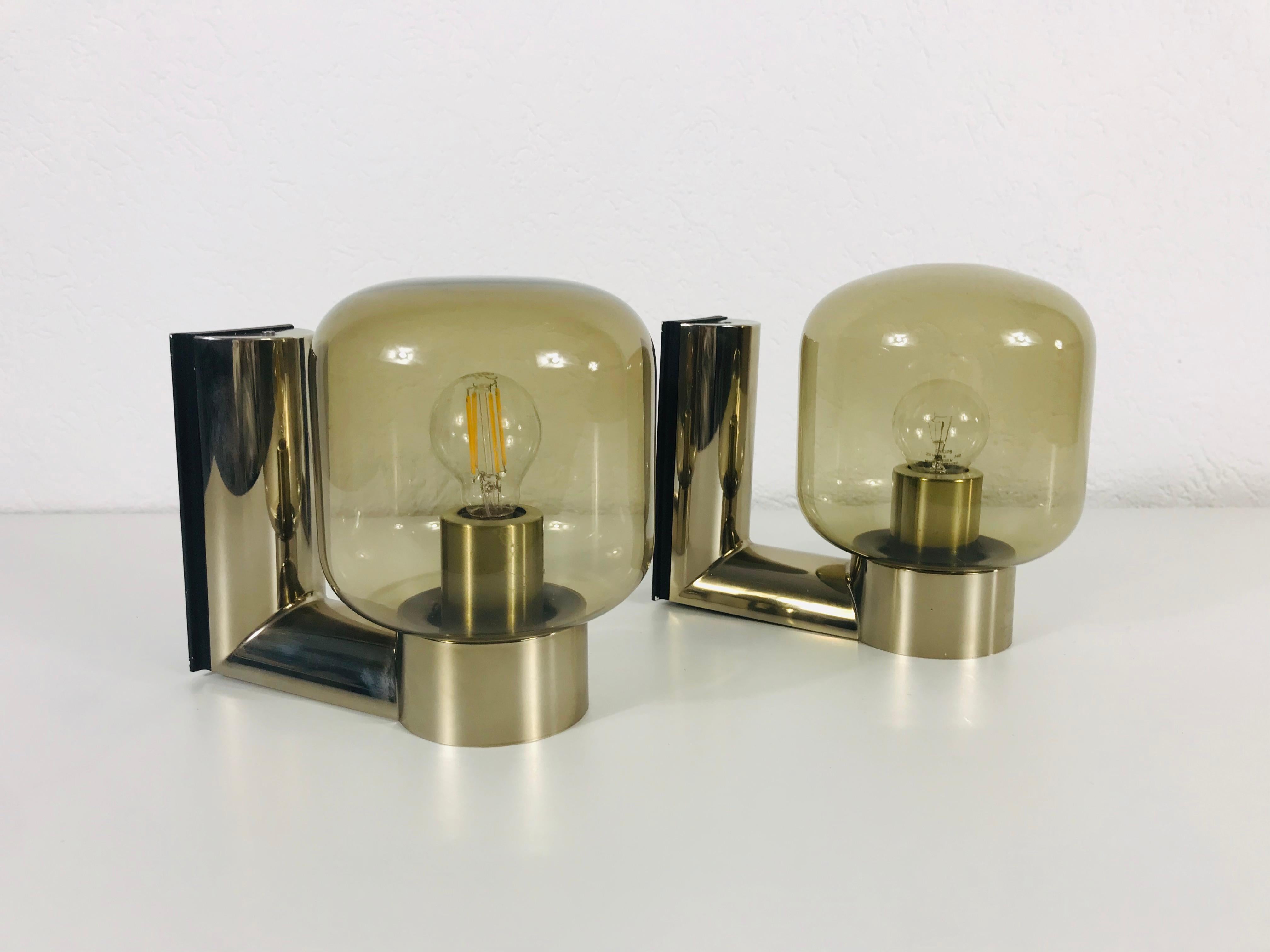 A wonderful set of 2 wall lights by the Japanese designer Motoko Ishii for the German brand Staff Leuchten. They have a very thin amber glass shade and a brass base.

The lights require E14 light bulbs. Works with 120/220 V. Very good vintage