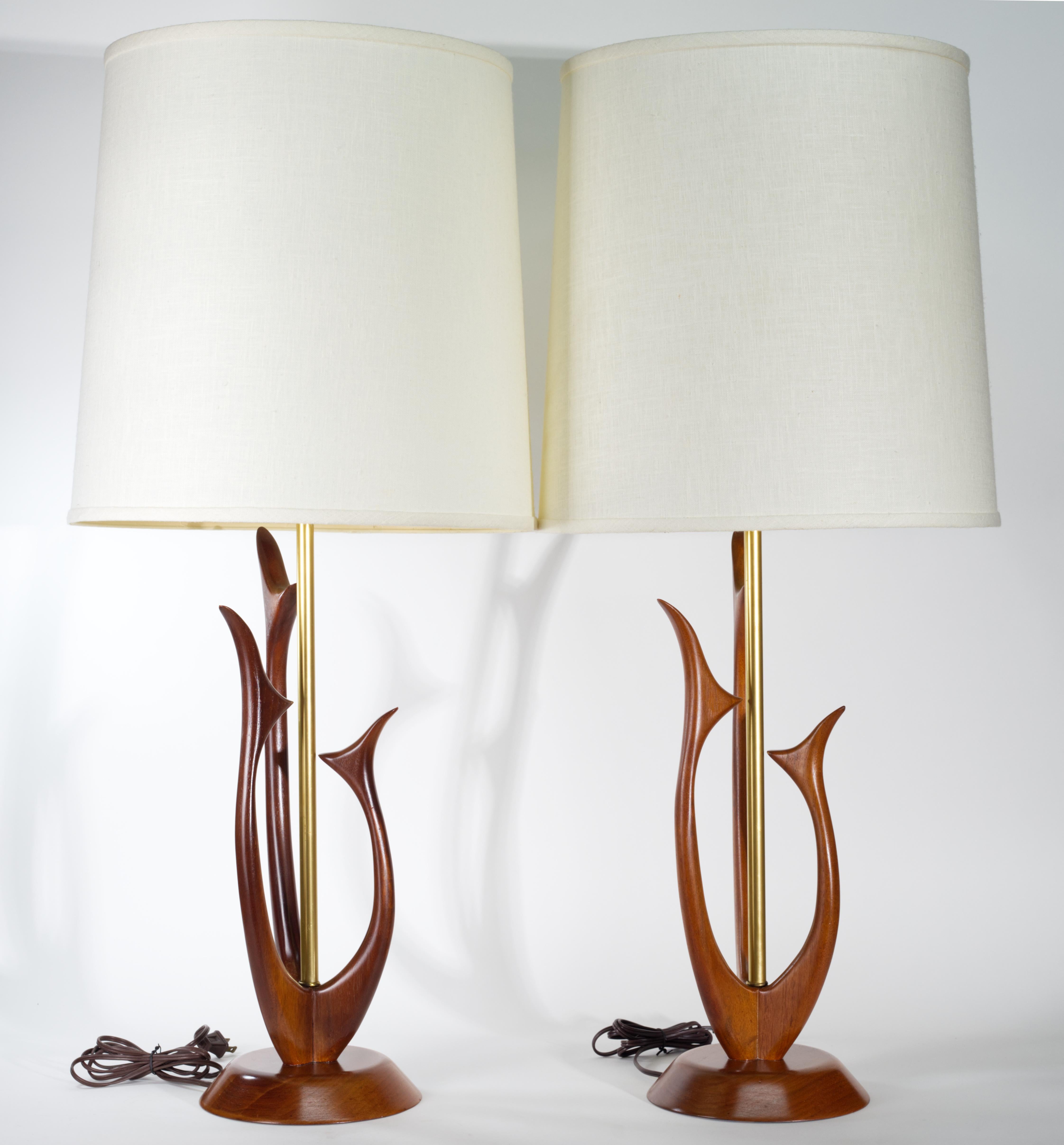 Sculptural Mid Century Modern lamps have walnut bodies in organic, biomorphic shapes mounted on round bases, with brass elements and hardware.

The lamps are signed with model numbers on bases under felt, but the manufacturer stickers are missing,