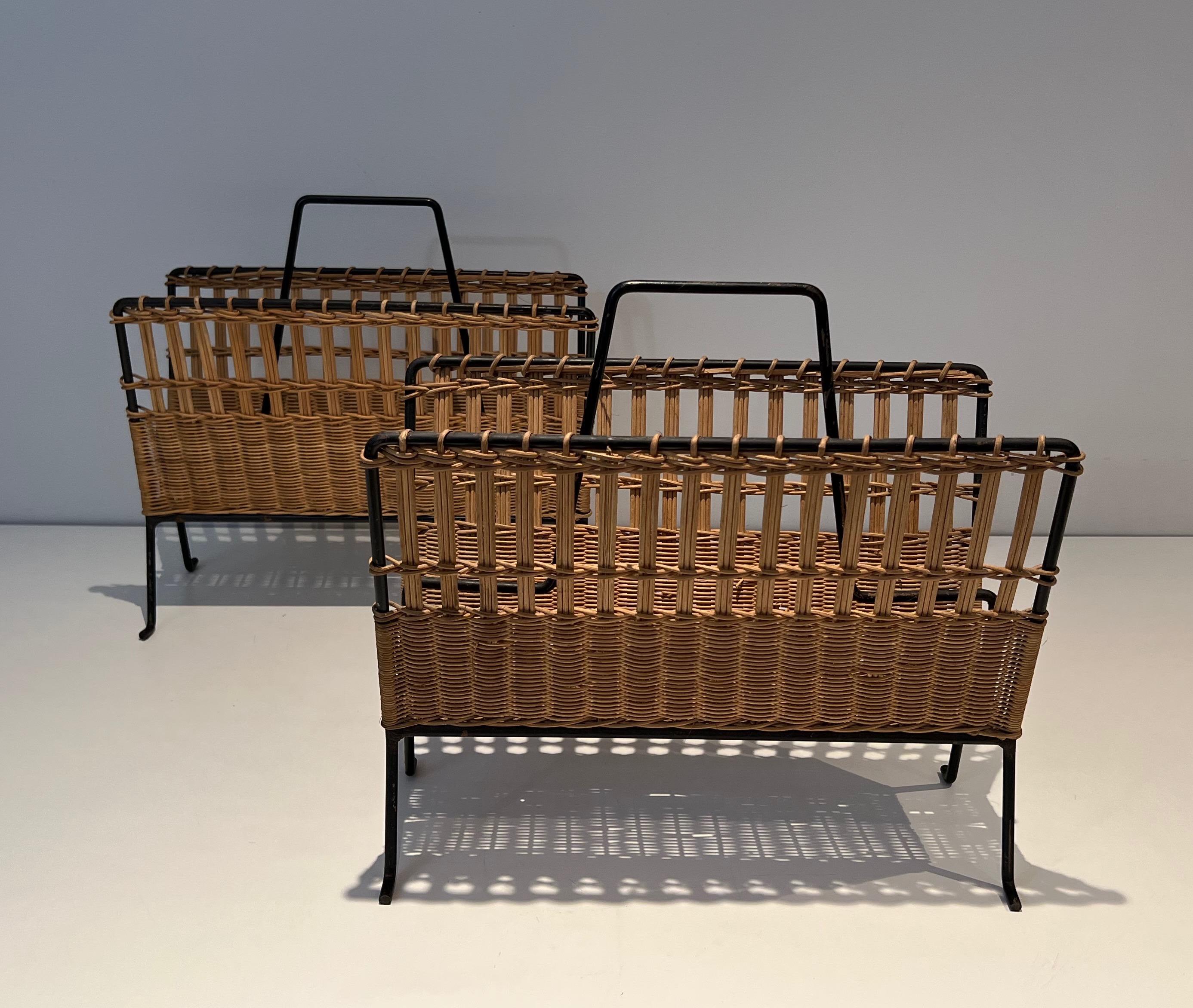 This pair of magazine racks is made of black lacquered metal and rattan. This is a nice and decorative model. This is a French work, circa 1950.